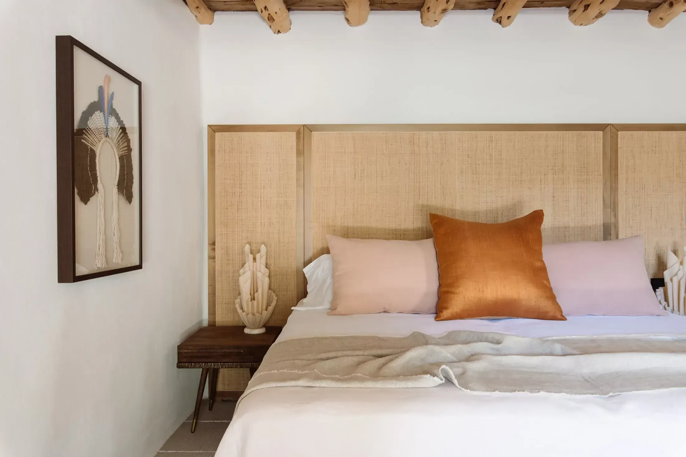 Finca La Inika, Balearic Islands — Bedroom with natural linen headboard, copper velvet pillow, wooden beams, and minimalist coastal décor.
