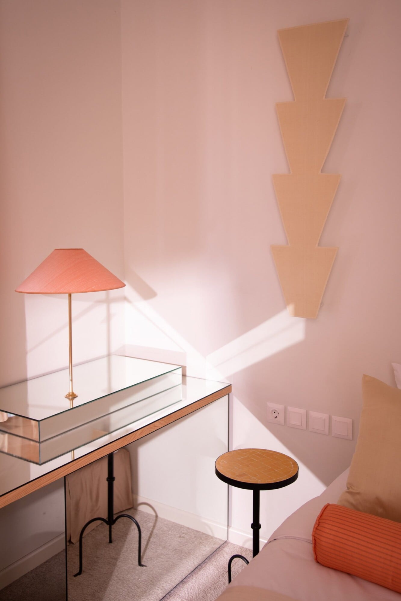 Apollo Palm, Europe — Minimalist hotel room with coral lamp, geometric wooden wall installation, and natural light casting geometric shadows on pink walls.