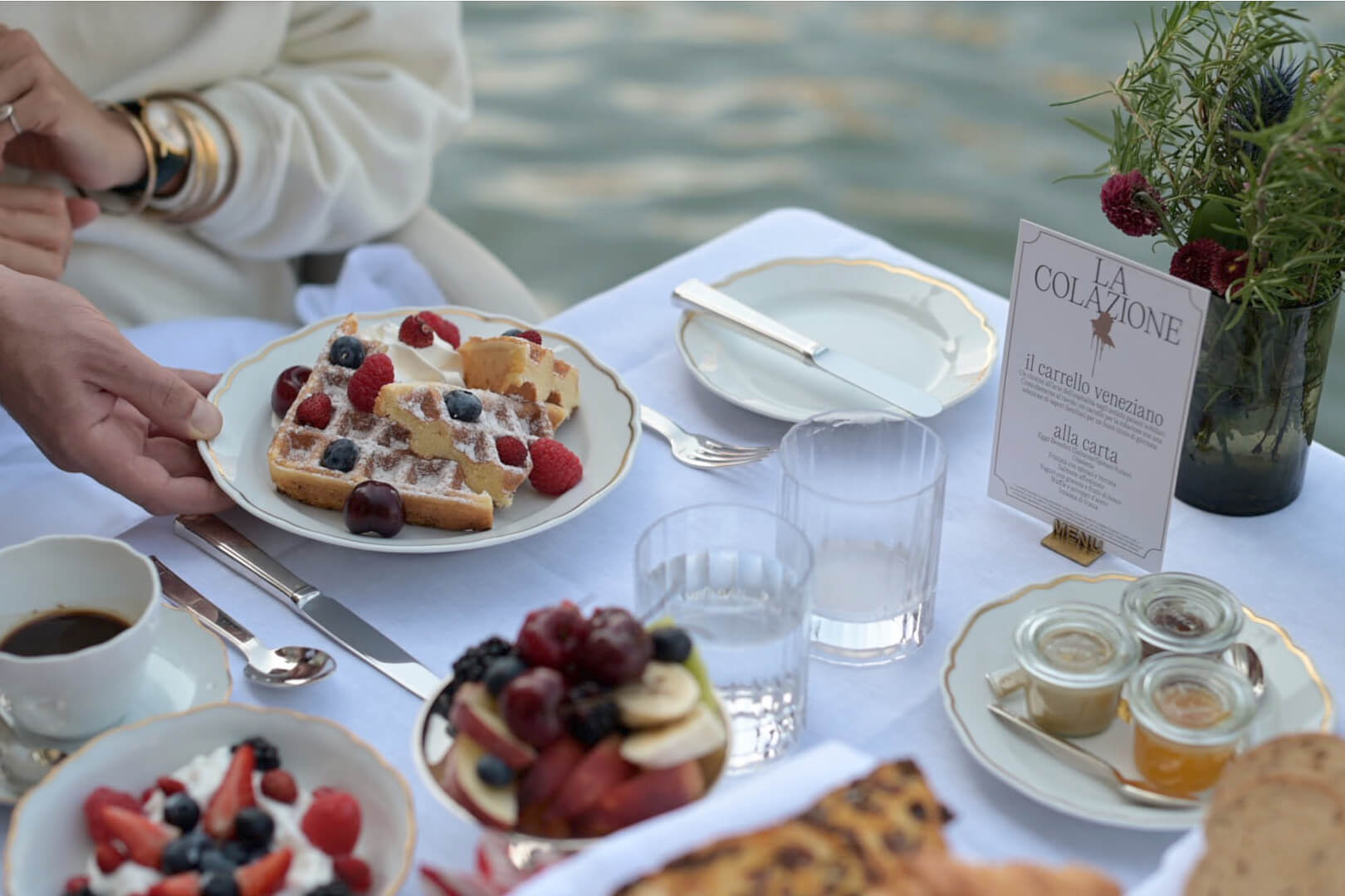 Breakfast On The Grand Canal — Waterside breakfast spread at La Colazione with waffles, fresh berries, coffee, and morning light reflecting off the Grand Canal.
