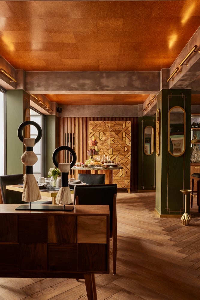 Campos Polanco, Mexico — Warm-toned luxury interior with copper ceiling, wooden herringbone floors, geometric wall art, and sculptural furniture in ambient golden light.
