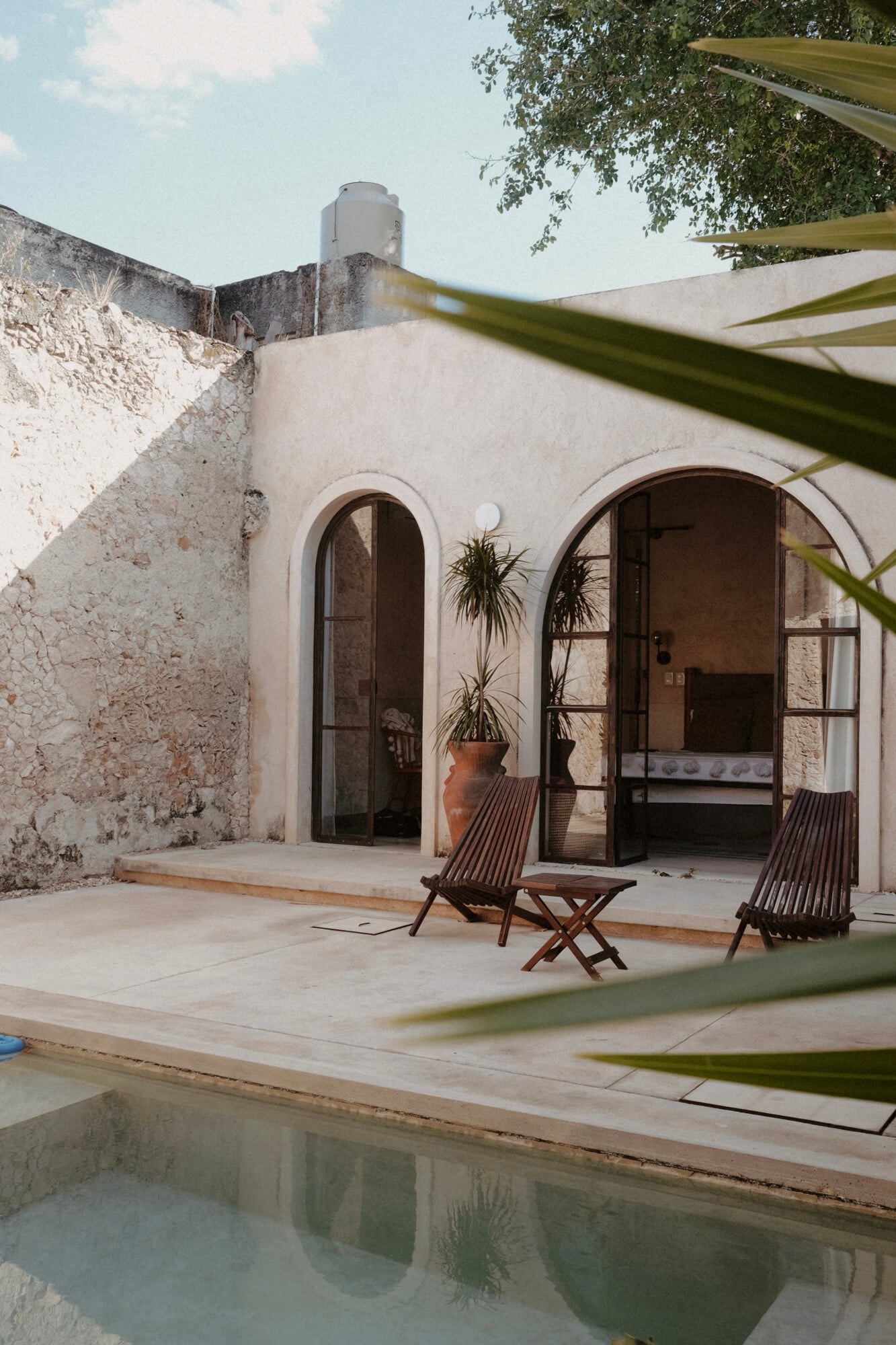 Casa Lohr, Mexico — Arched stone villa with terracotta planter, wooden deck chairs, and pool reflecting modernist architecture and desert landscape.