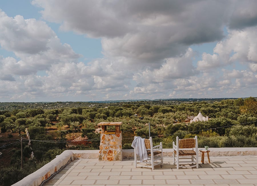 Masseria Moroseta, Europe — Rooftop terrace with whitewashed chairs overlooking olive groves and rolling countryside under clouded sky.