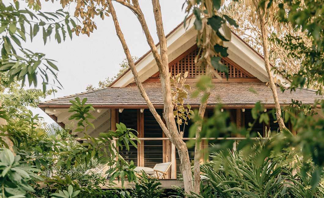 Islas Secas, Panama — Wooden pavilion with pitched roof nestled among tropical palms and dry-season foliage, open-air design with natural materials and covered veranda.