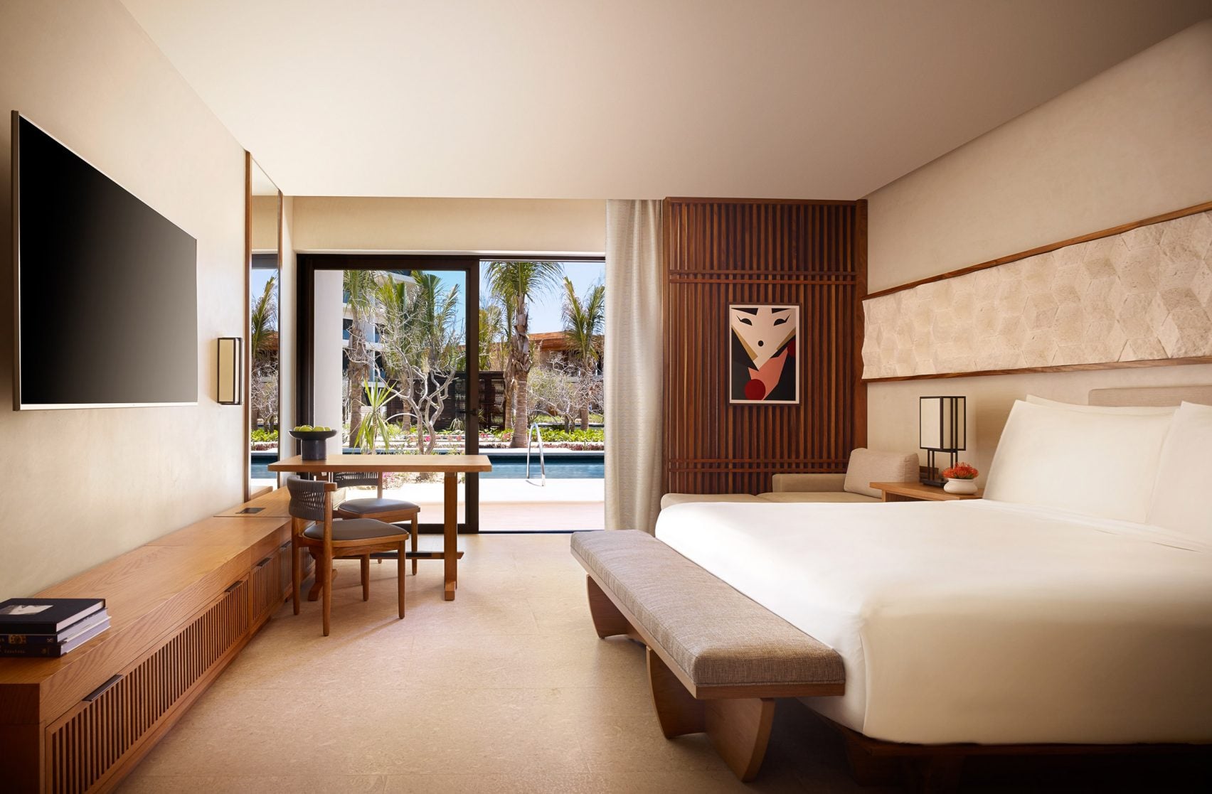 Nobu Los Cabos, Mexico — Modern luxury bedroom with warm wood furnishings, coastal views, palm trees, and minimalist Japanese-inspired design elements.