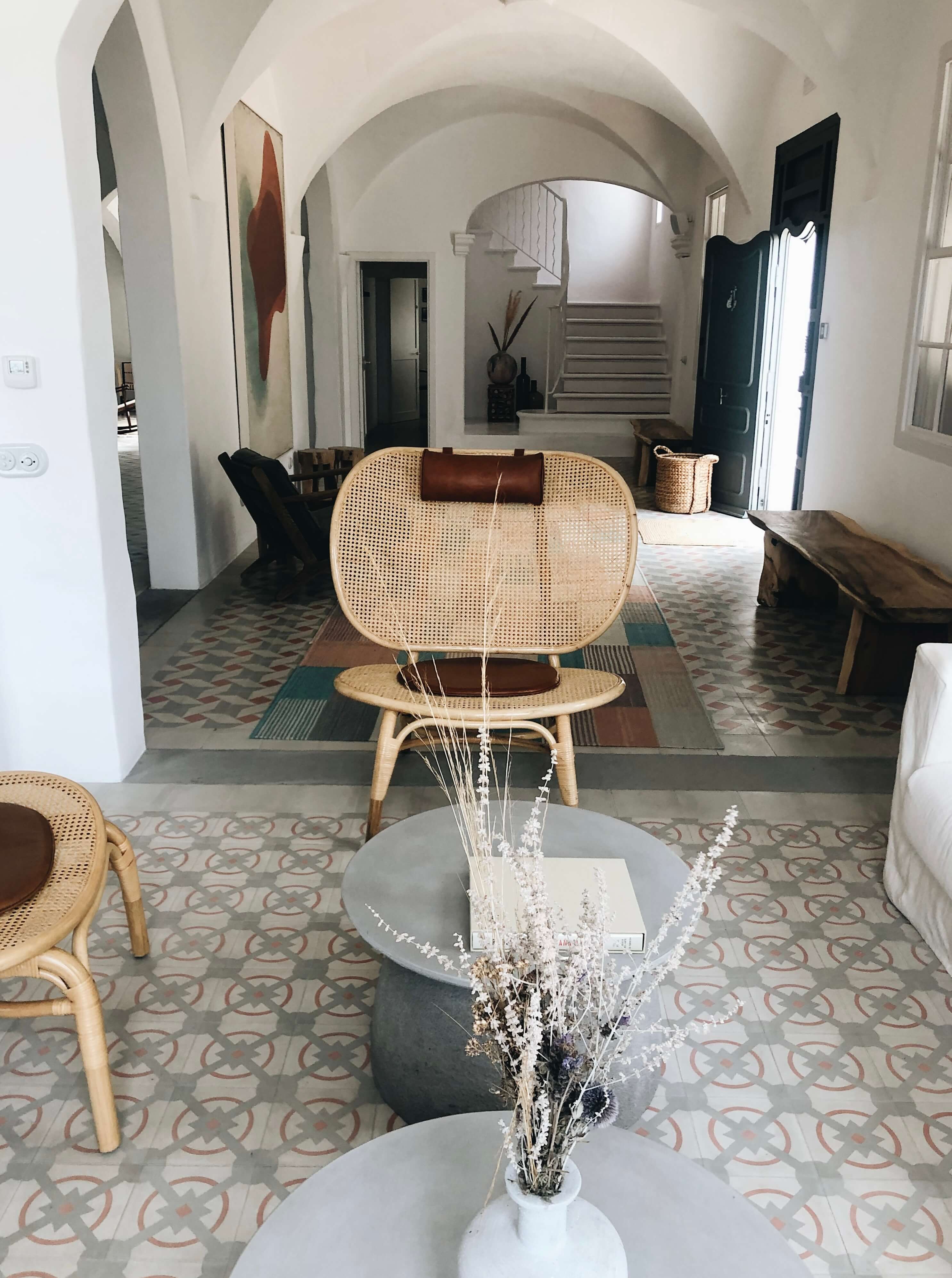 Es Bec d’Aguila — Es Bec d'Aguila, Balearic Islands, Spain — Arched entryway with rattan chairs, geometric tile floor, white plaster vault, and minimalist floral arrangement in modern hospitality interior.