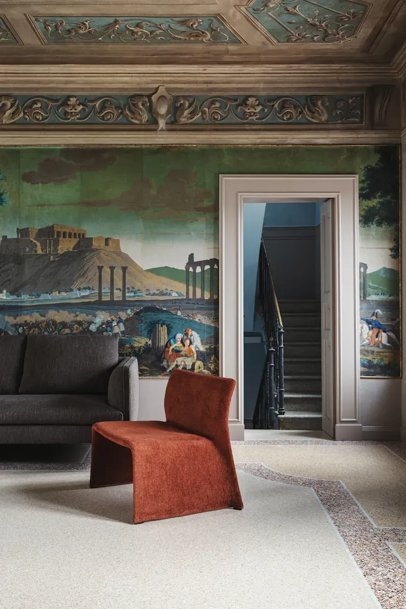 Roncolo 1888, Europe — Neoclassical room with frescoed ceiling, terracotta chair, green wall murals of classical ruins, and marble flooring.