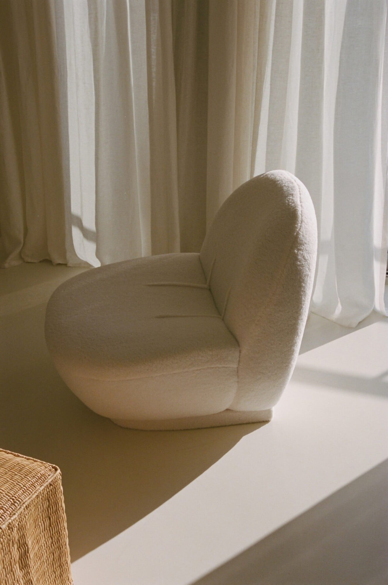 Apollo Palm, Europe — Cream boucle curved armchair by window with flowing sheer curtains, minimalist luxury interior design detail.