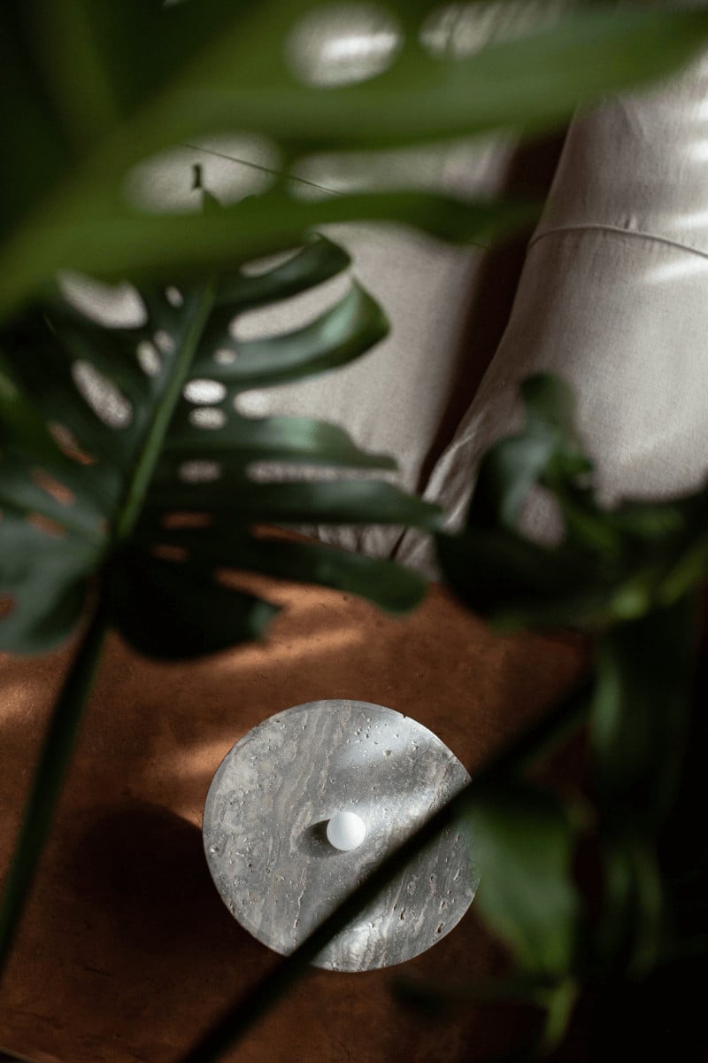 Further Hotel, Asia — Concrete sculptural vessel with white stone detail beside green fern fronds and natural linen, minimalist hotel design aesthetic.