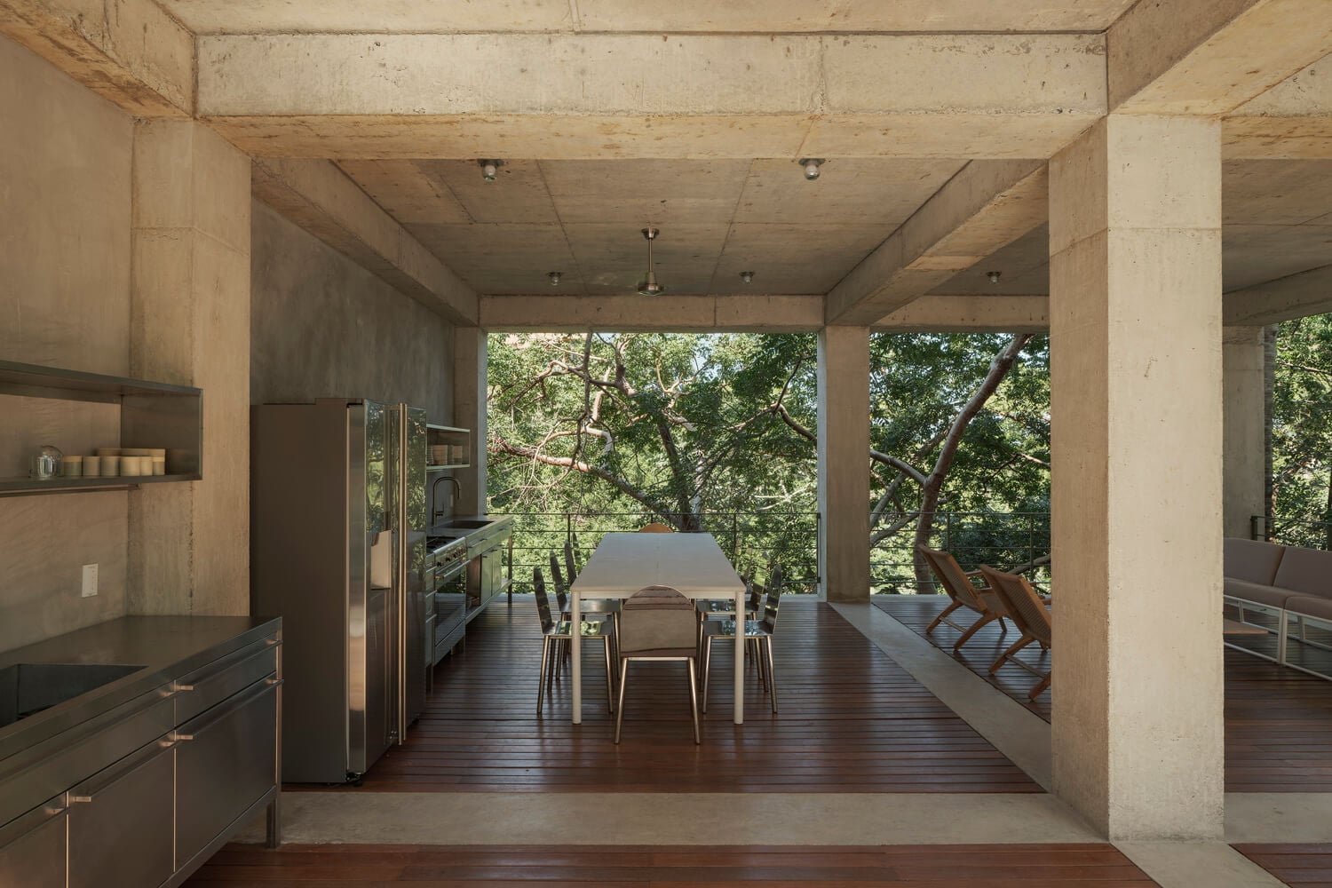 NICO, Mexico — Concrete pavilion with kitchen and dining table overlooking forested landscape, natural light filtering through open structure.