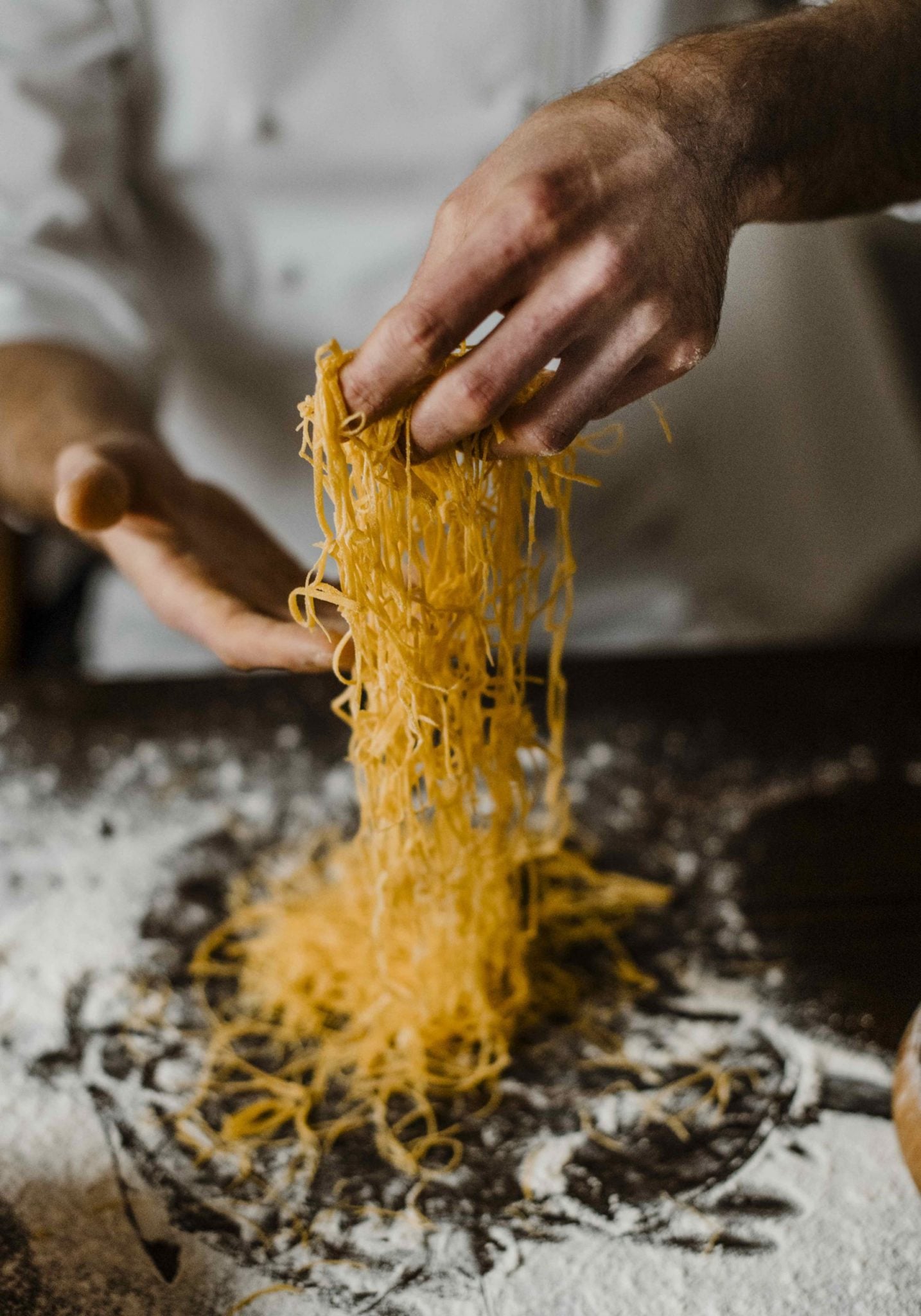 Cooking Classes — Fresh pasta being lifted from flour and semolina surface during hands-on cooking class in European culinary studio.