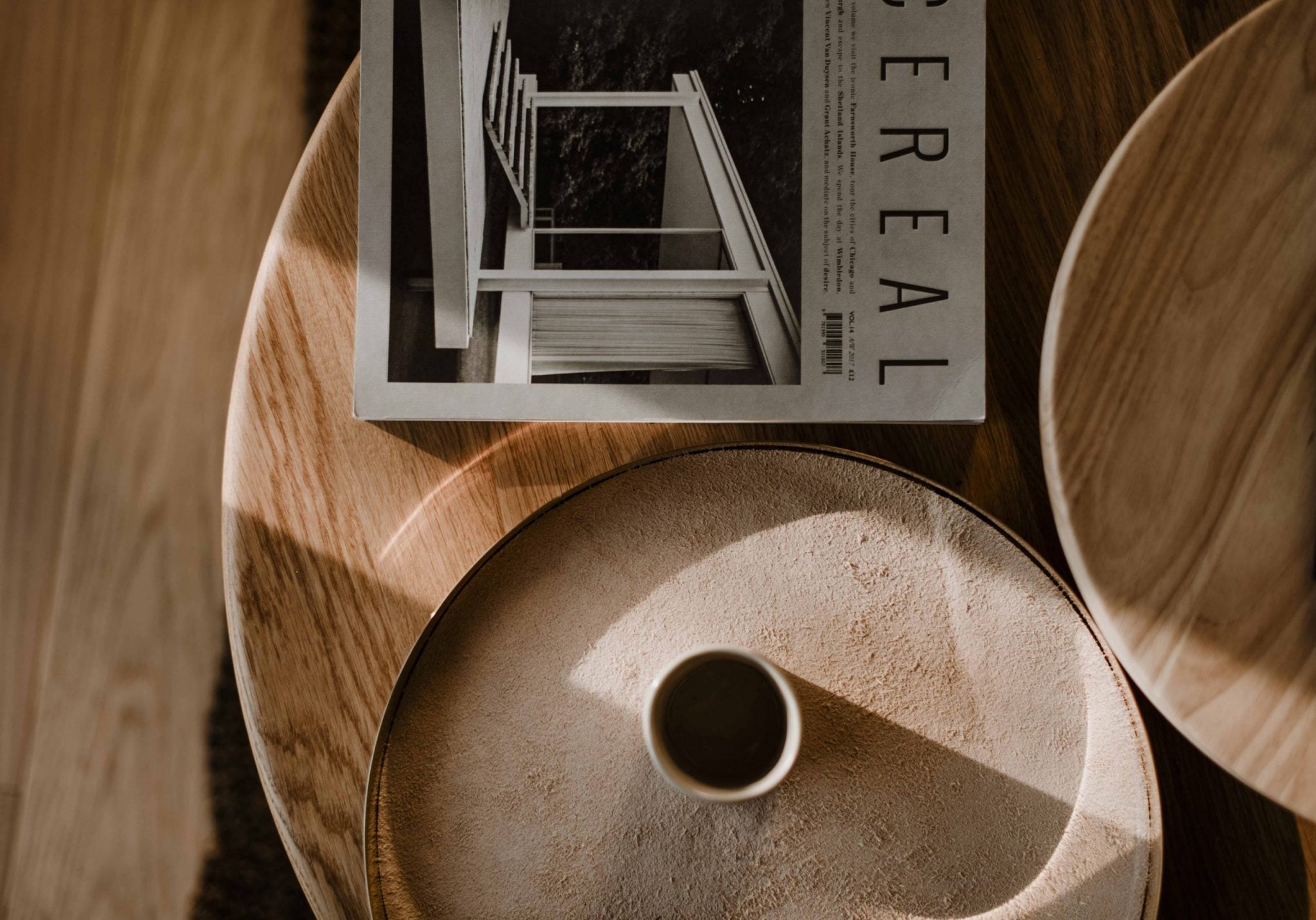 Casa di Langa, Europe — Minimalist concrete vessel with central aperture beside architectural magazine and wooden chairs in natural light.