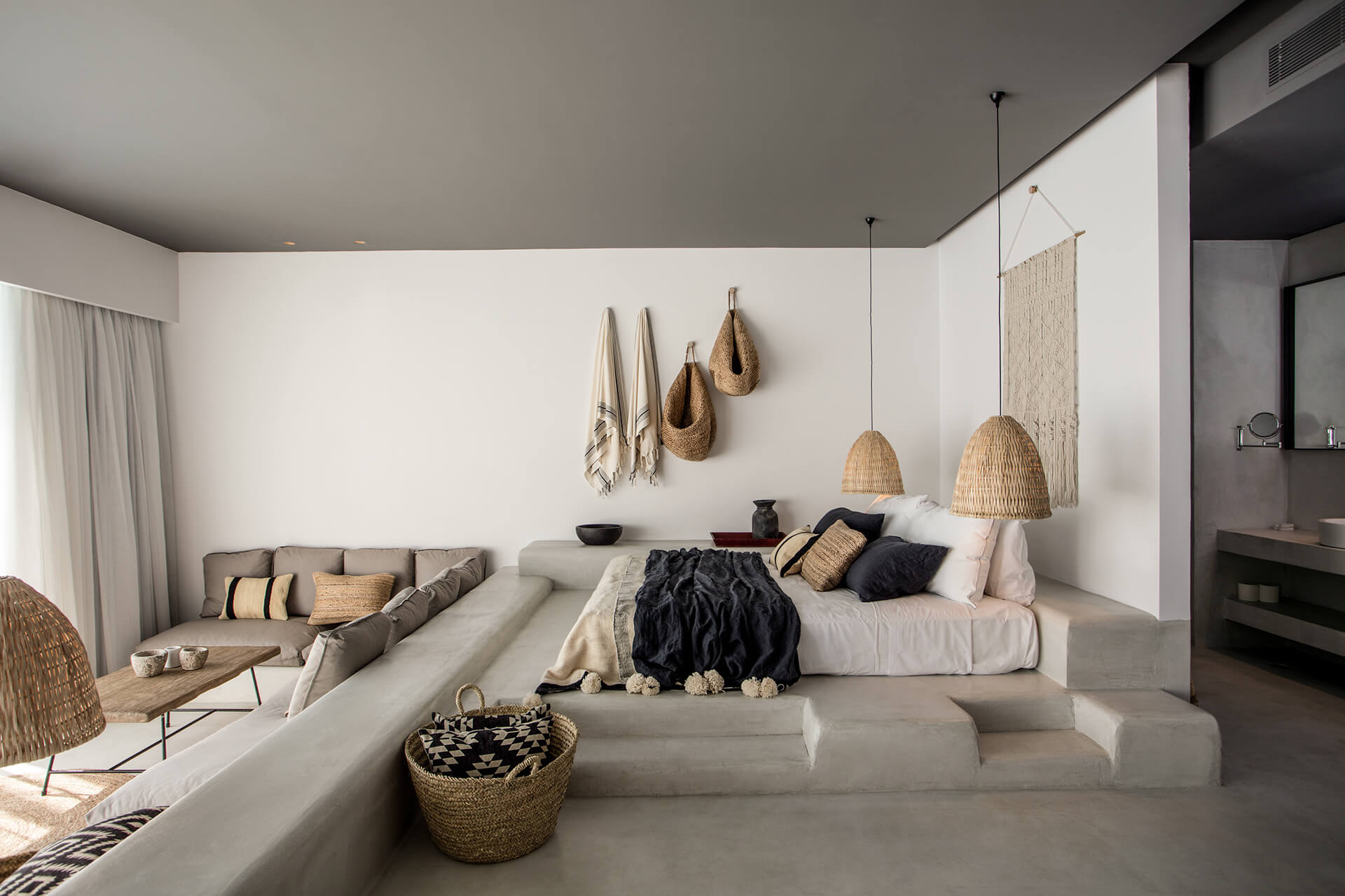 Casa Cook Rhodes, Europe — Minimalist bedroom with woven pendant lights, natural fiber wall hangings, cream linens, and stepped platform bed in neutral coastal aesthetic.