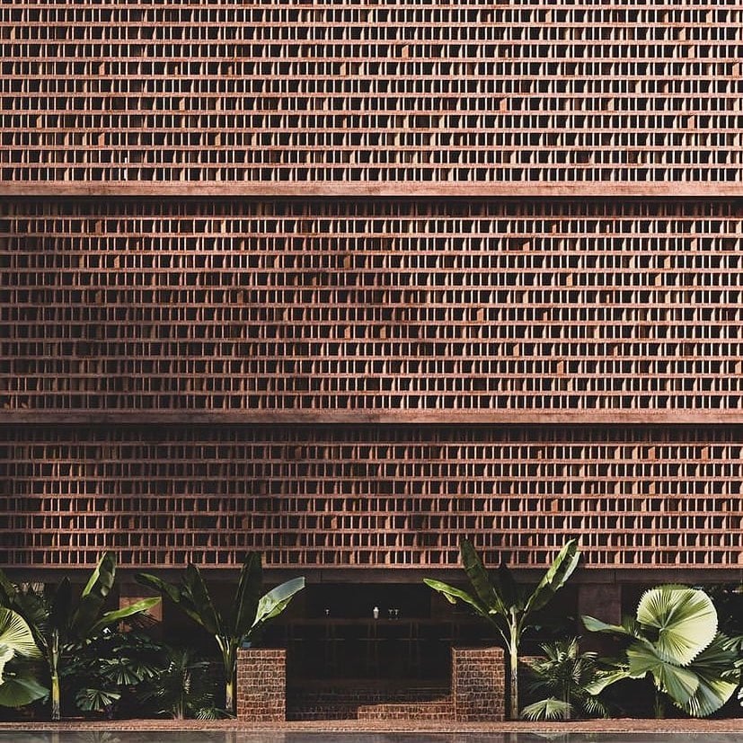Further Hotel, Asia — Minimalist brick facade with rhythmic window pattern and tropical palms at ground level, modernist hospitality architecture.