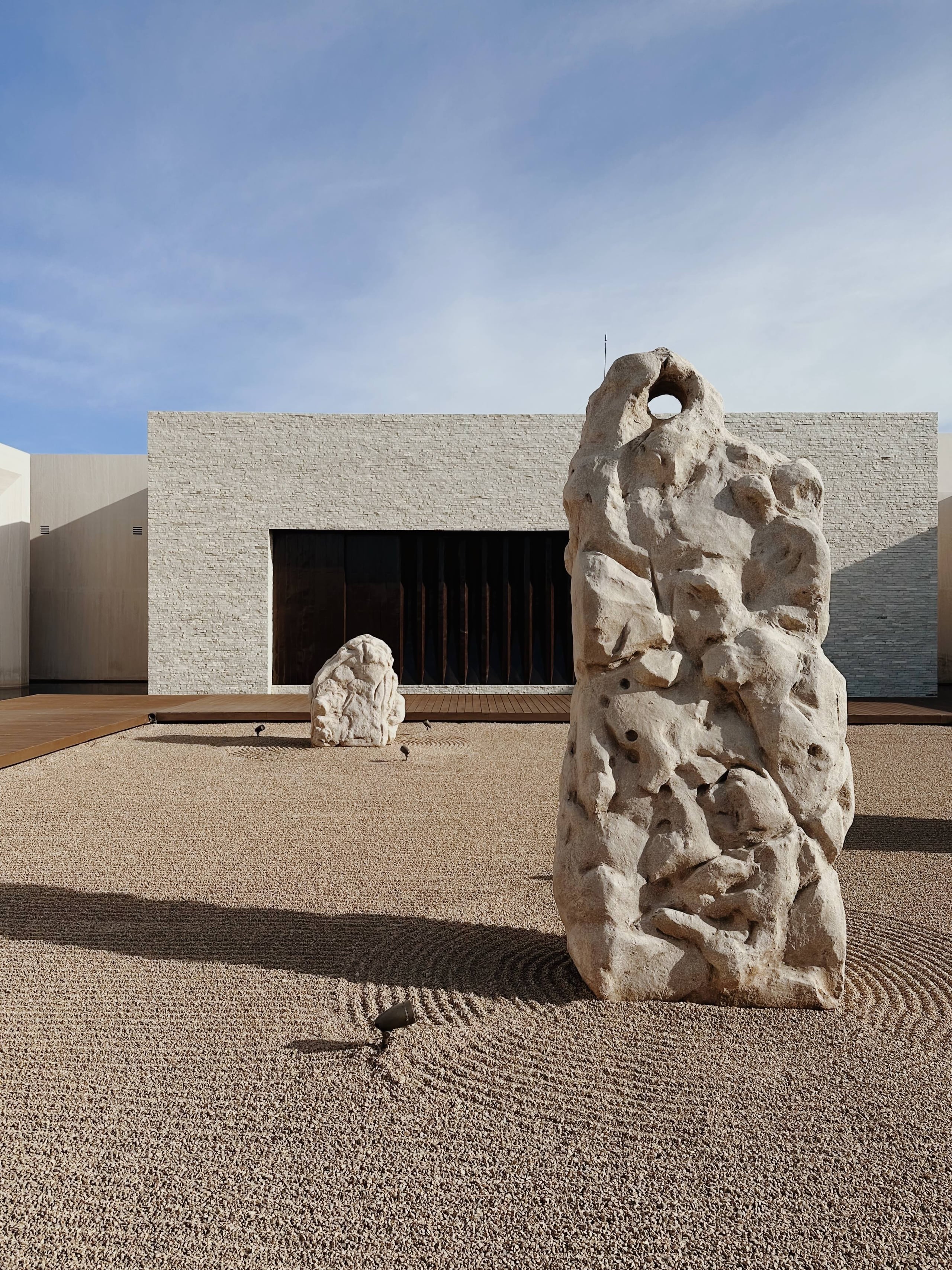 Nobu Los Cabos, Mexico — Sculptural stone figures in minimalist courtyard with raked sand, modernist architecture, and clear desert light.