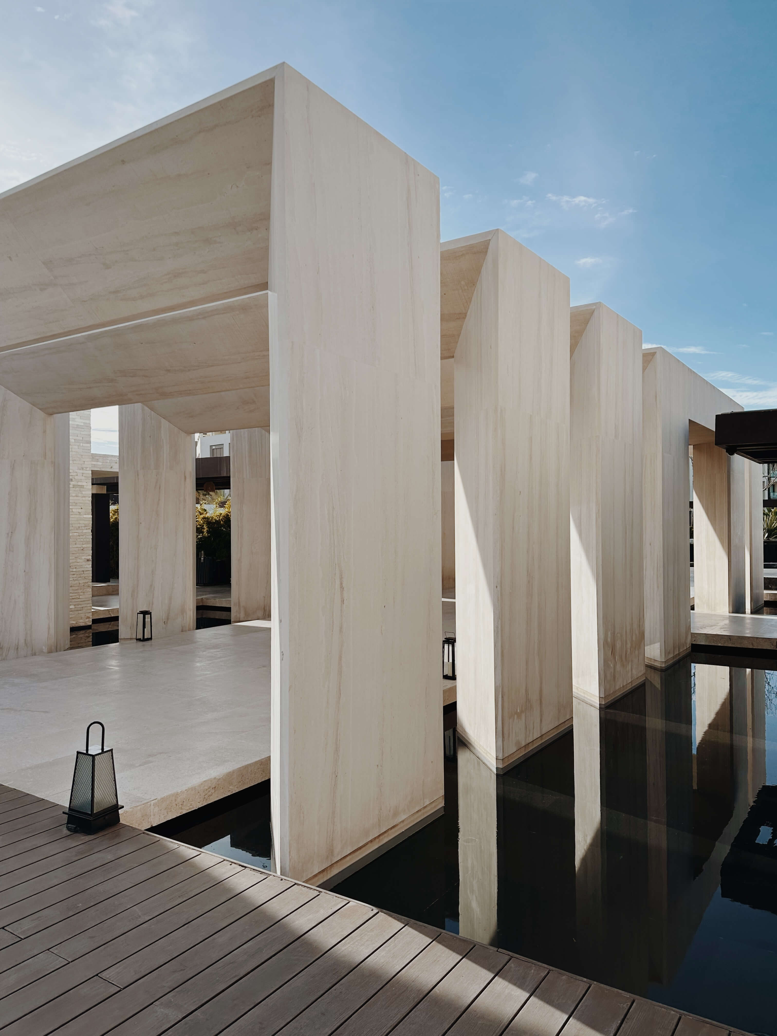 Nobu Los Cabos, Mexico — Minimalist travertine pavilions with clean geometric forms reflected in still water, bathed in natural light.