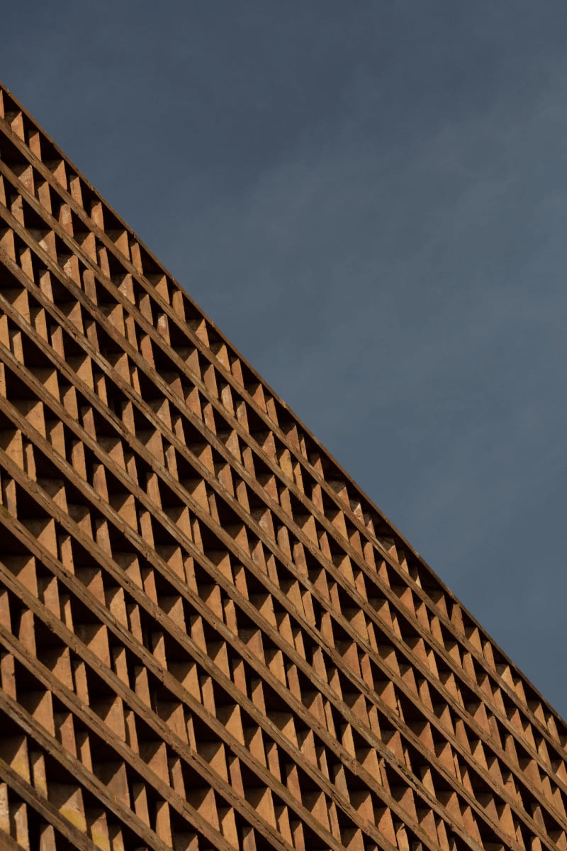 Further Hotel, Asia — Geometric brick facade with diamond cutout pattern casting angular shadows against clear sky, modernist architecture detail.