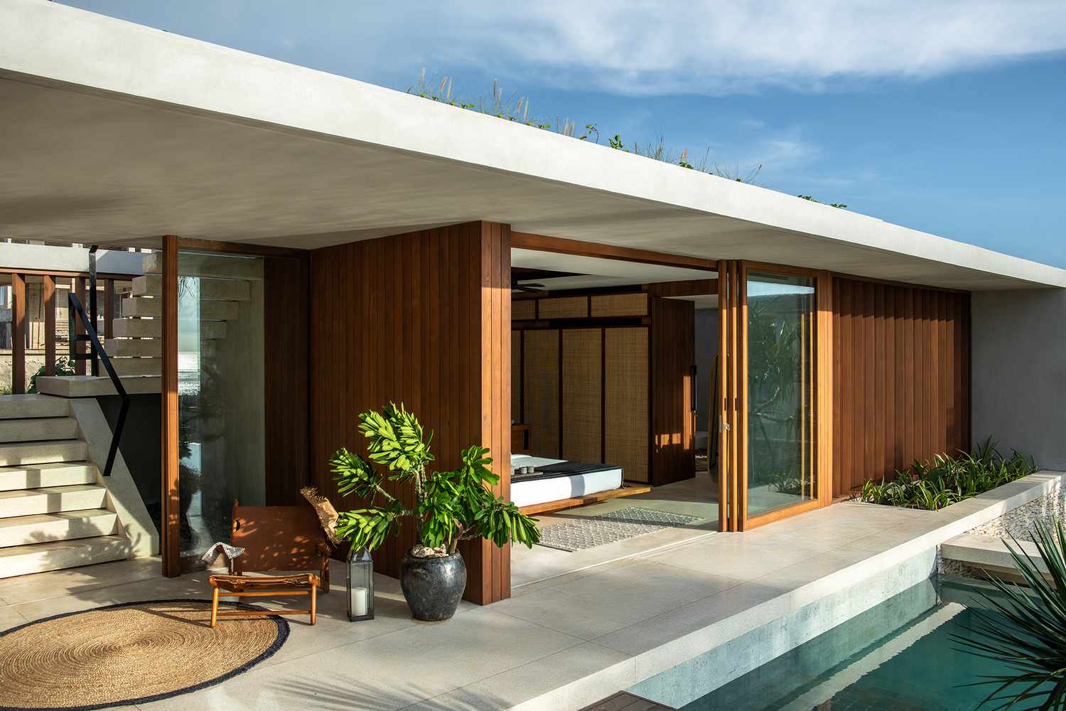 Cap Karoso, Asia — Modern pavilion with teak wood screens, concrete soffit, and open-air bedroom overlooking pool, tropical minimalist design.