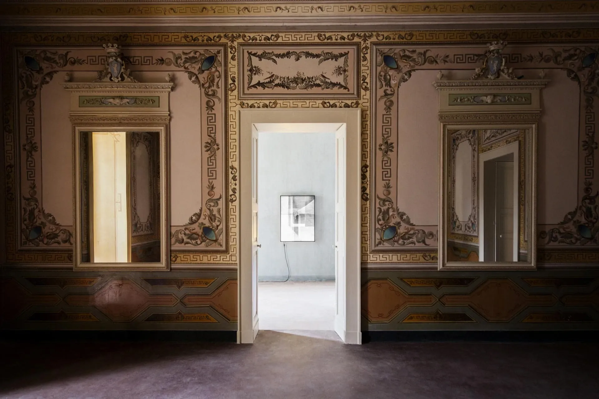 Palazzo Daniele, Europe — Neoclassical room with ornate gold-framed mirrors, frescoed ceiling details, geometric inlays, and bright doorway opening to modern gallery space.
