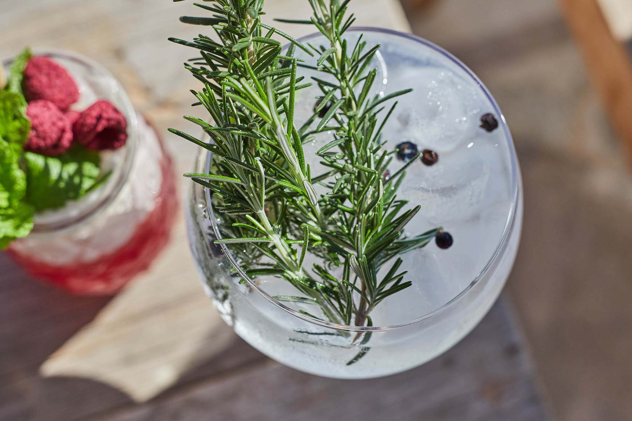 Finca Serena, Balearic Islands, Spain — Craft cocktails with rosemary sprigs and juniper berries on limestone surface, natural light hospitality styling.