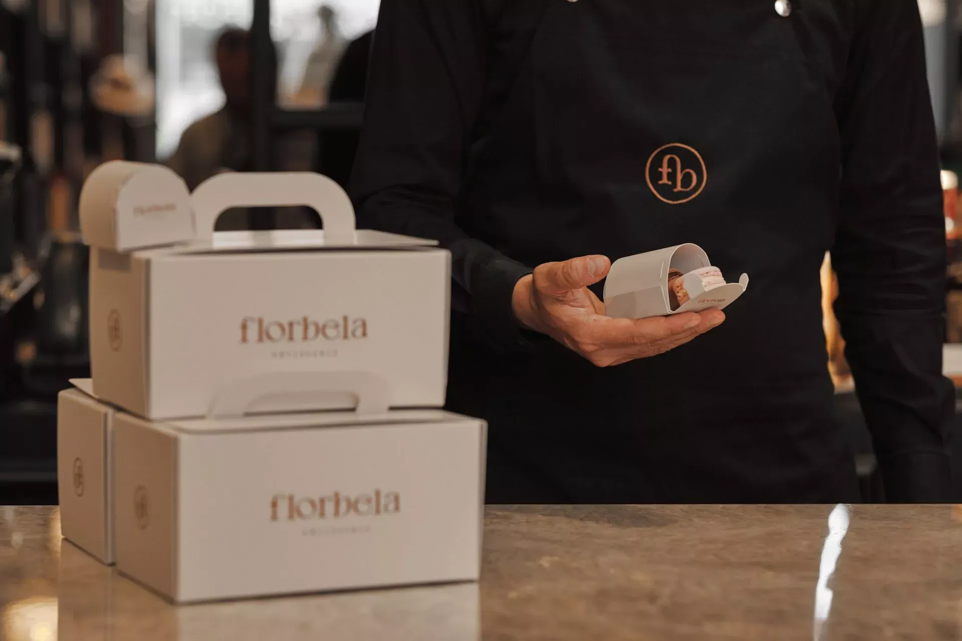 Florbela, Portugal — Cream branded packaging and ceramic vessel displayed on wooden counter, luxury hospitality branding detail with warm neutral aesthetic.