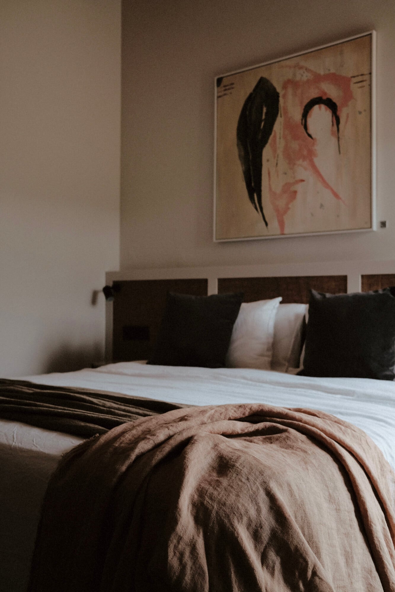 Vista Verde, Balearic Islands — Modern bedroom with dark wood headboard, white linens, beige throw, and abstract black and red artwork on neutral wall.