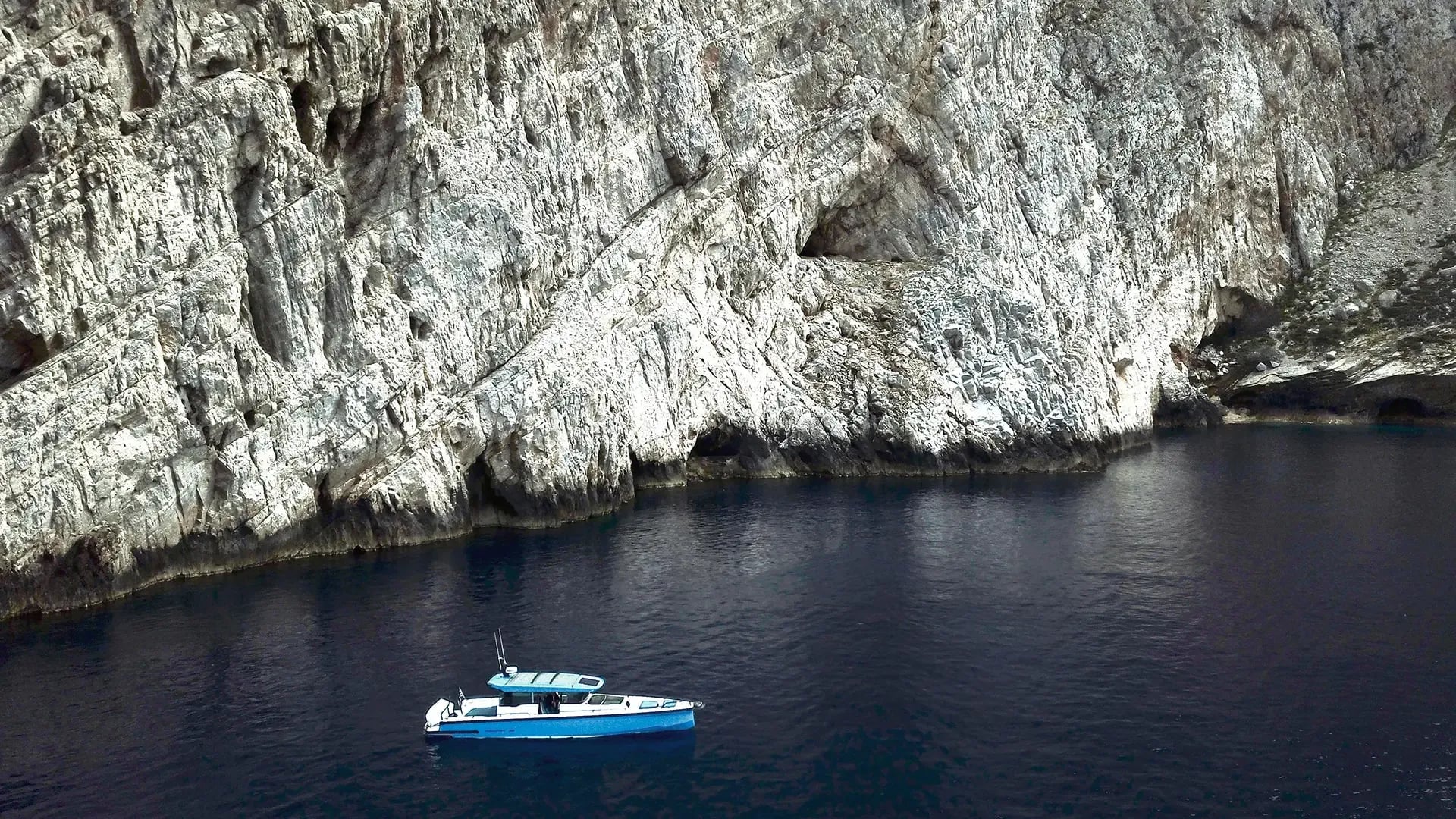 Boat Trip — Moored blue fishing boat against white limestone cliffs, Aegean Sea, Greece — coastal Mediterranean escape and scenic boating experience.