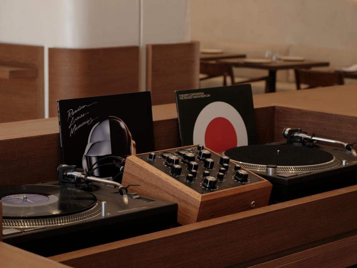 Gundari, Greece — DJ setup with wood-paneled mixer, turntables, vinyl records, and headphones in minimalist hospitality interior