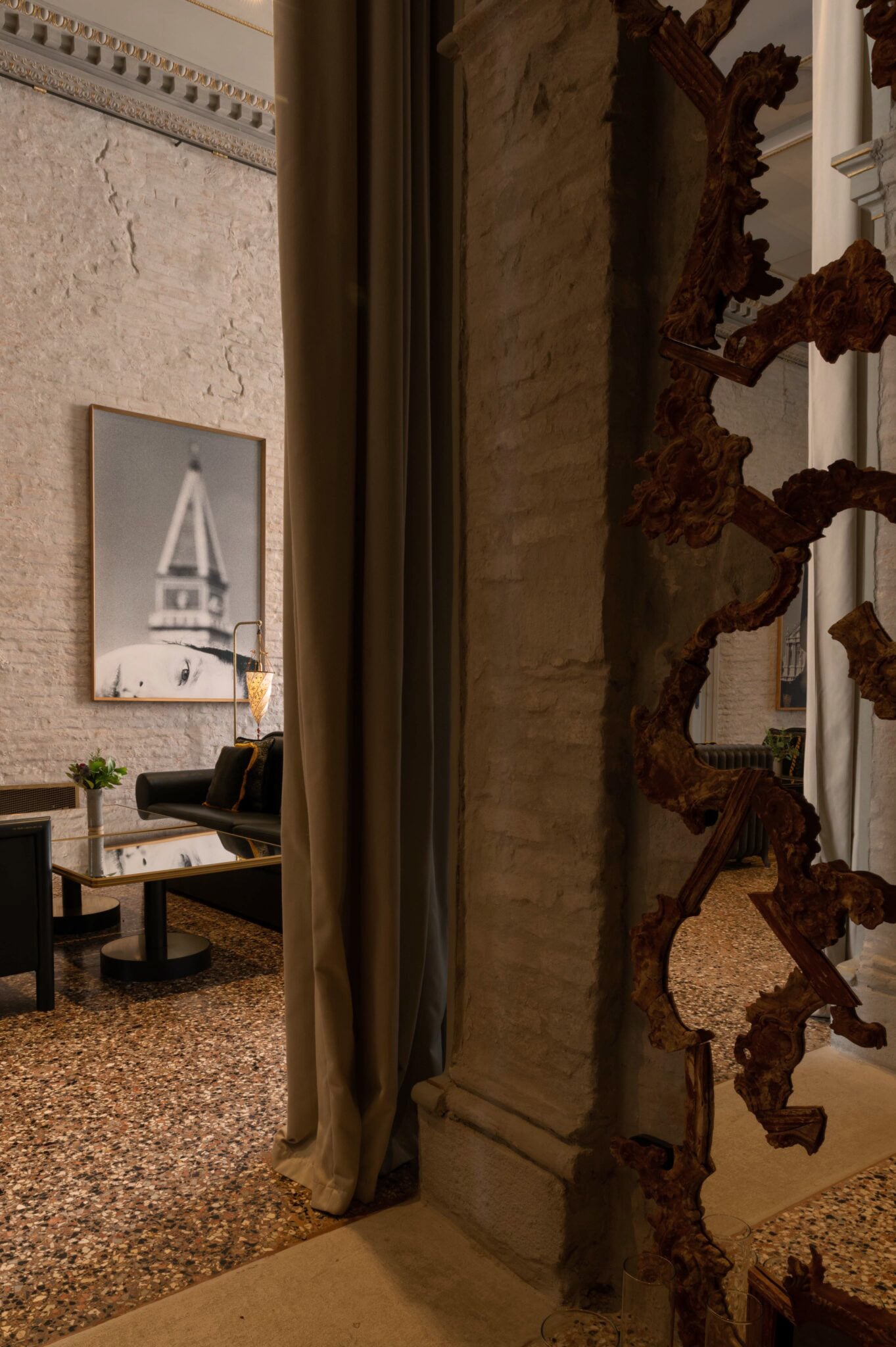The Venice Venice Hotel, Venice, Europe — Ornate wooden architectural detail frames view of textured stone corridor with terrazzo flooring and modern seating area beyond.