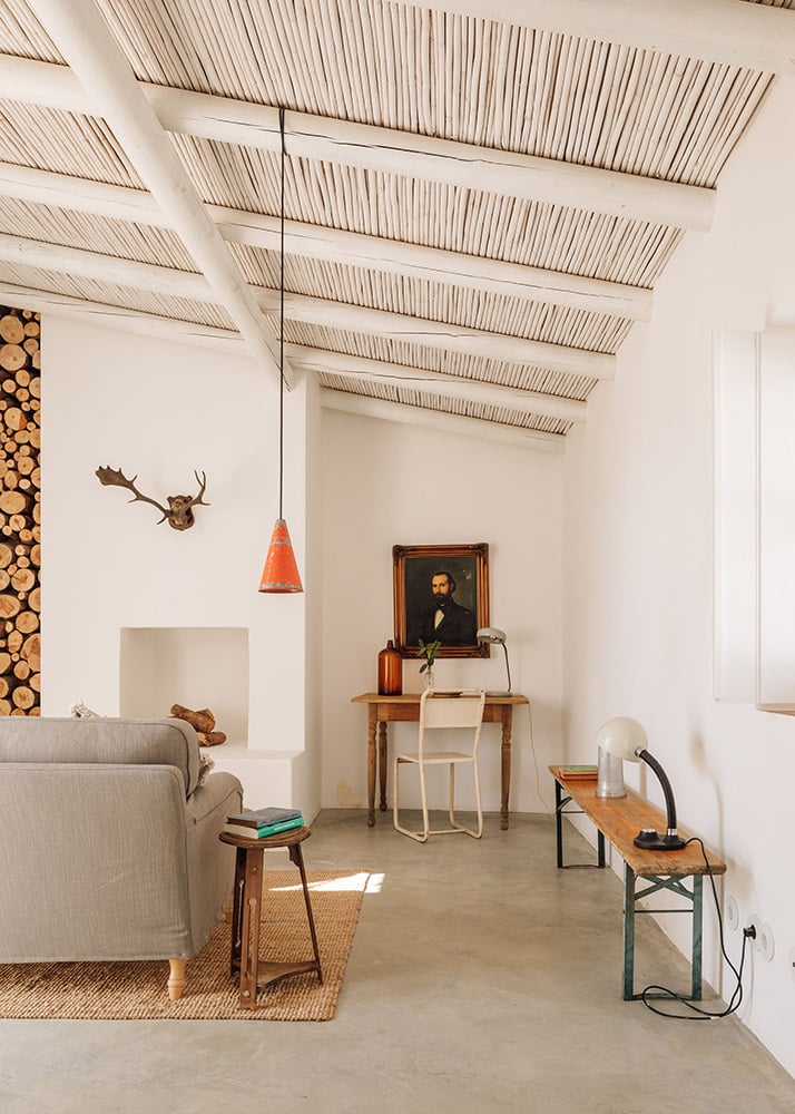 Hospedaria, Europe — Minimal loft with exposed beam ceiling, concrete floors, vintage furnishings, and natural light filtering through skylight panels.