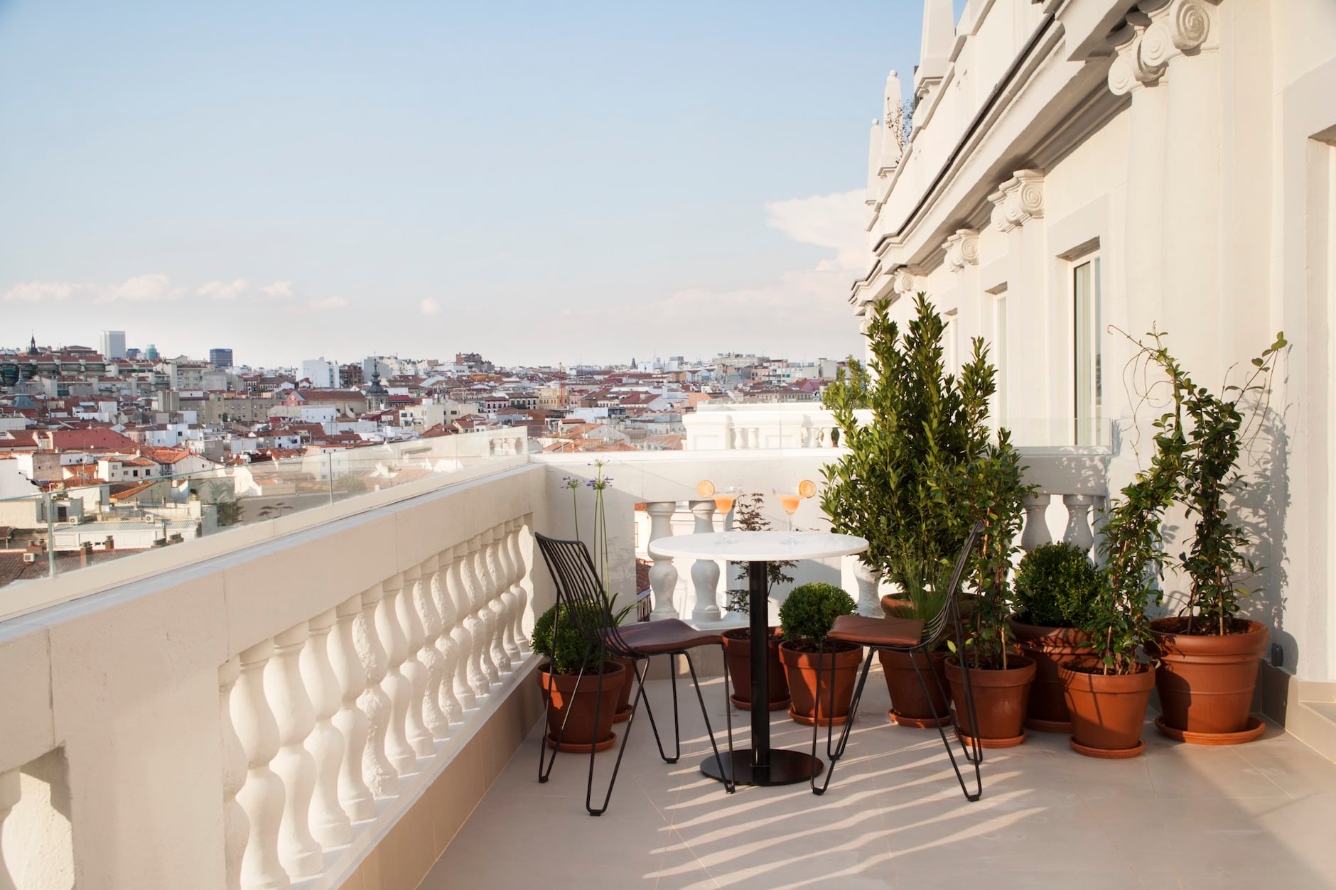 Dear Hotel, Istanbul, Turkey — Rooftop terrace with panoramic city views, modernist white balustrade, potted greenery, mid-century chairs, afternoon light casting geometric shadows.