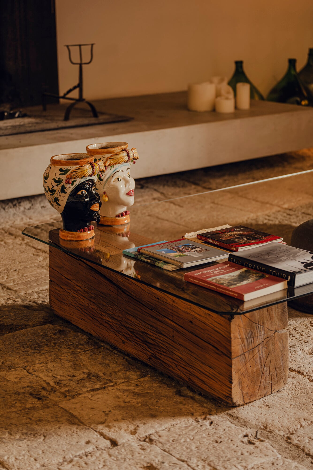 Susafa, Italy — Wooden bench with stacked design books and hand-painted ceramic head vessels, warm studio lighting, minimalist interior.