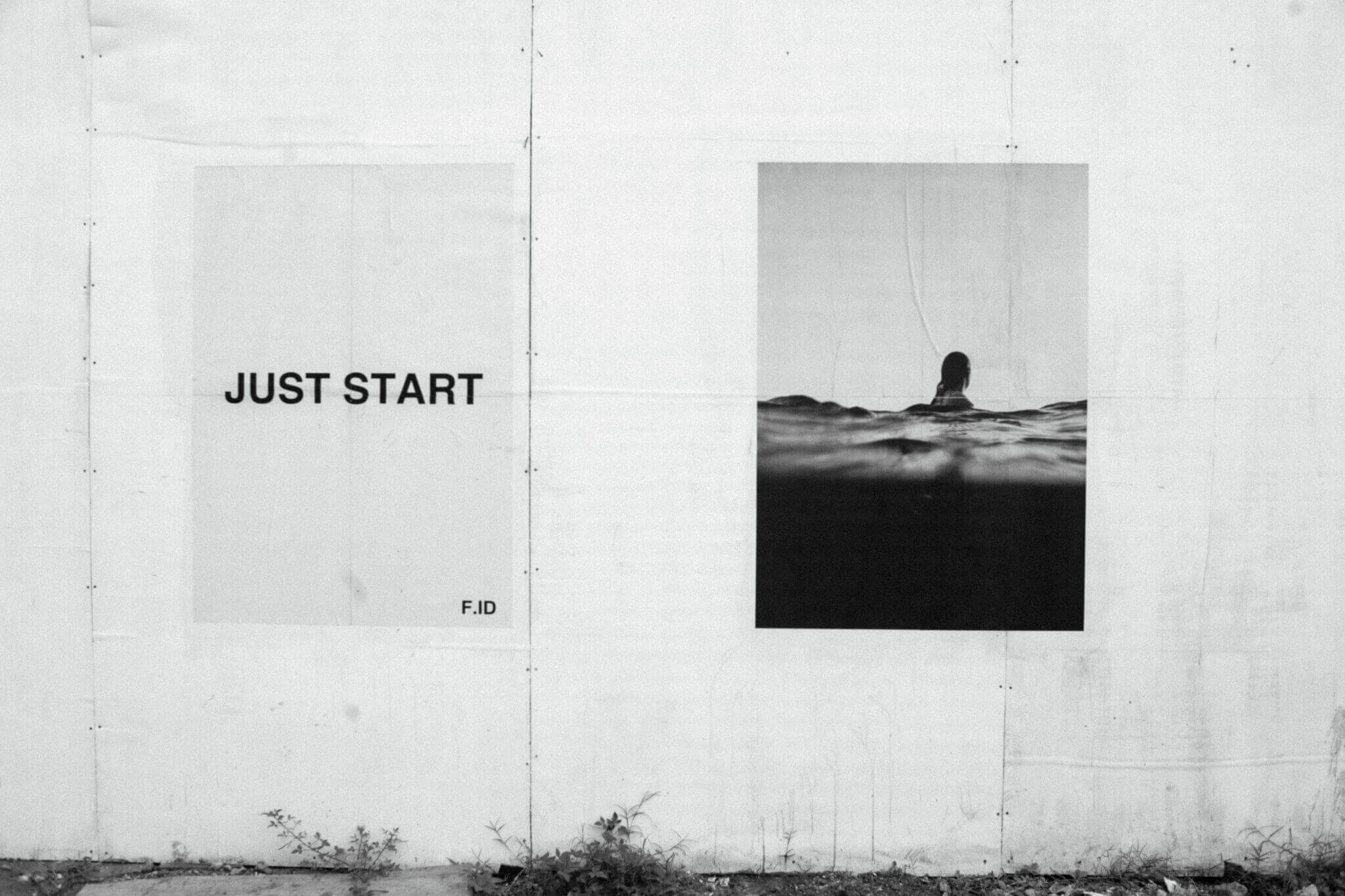 Further Hotel, Asia — Minimalist gallery wall with "JUST START" text and black-and-white photograph of swimmer in water, concrete aesthetic.