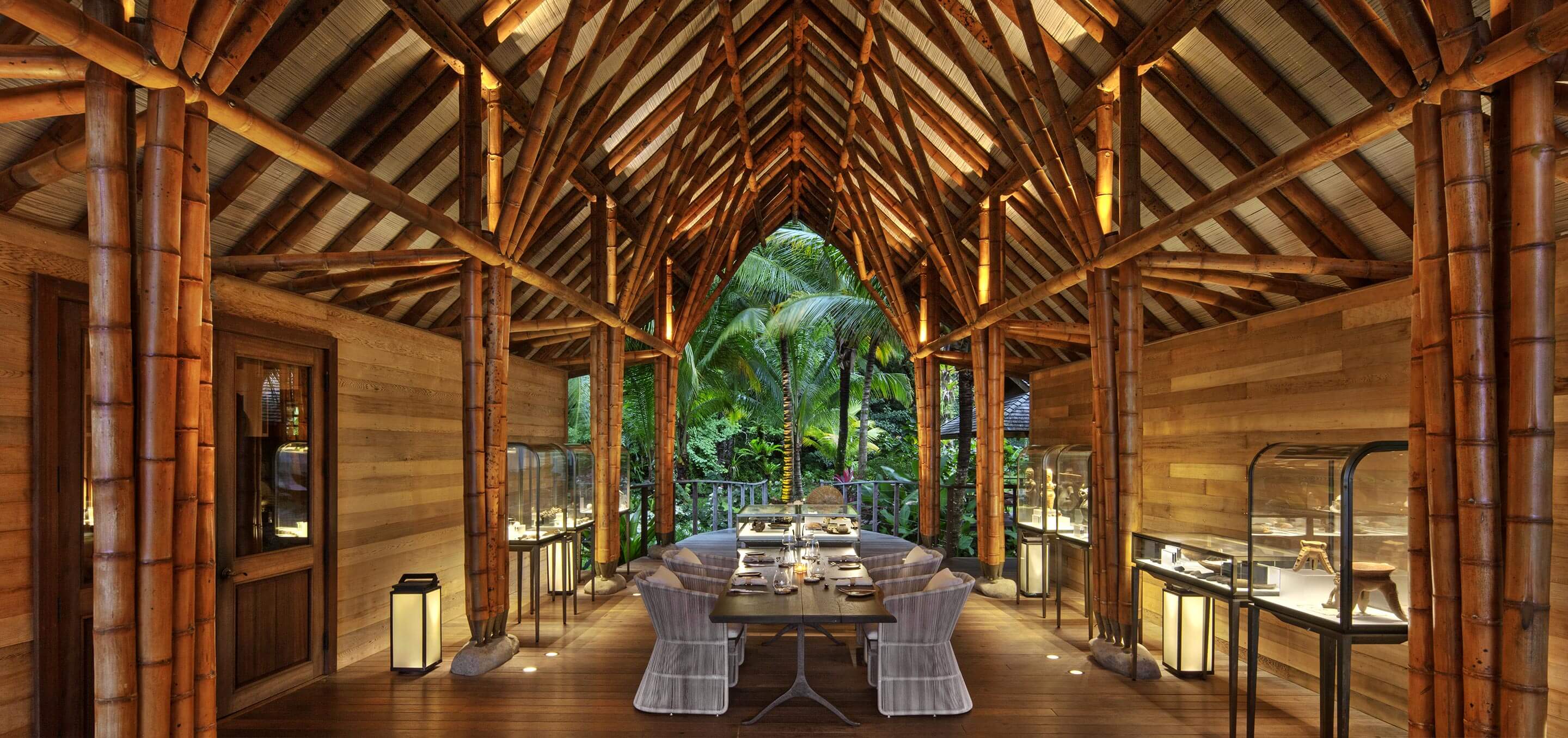 Islas Secas — Timber pavilion with soaring gabled roof, bamboo columns, and open-air dining overlooking tropical palms at sunset.