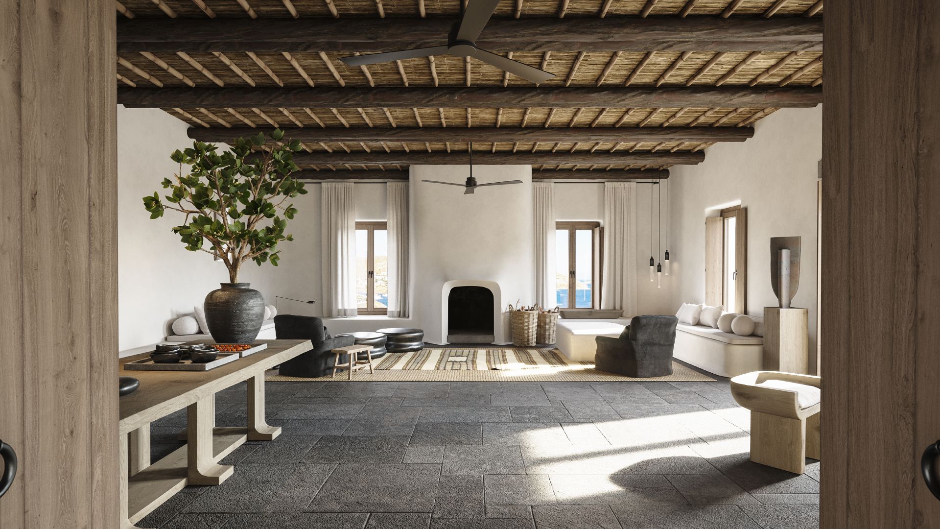 Kalesma, Europe — Minimalist living room with exposed timber ceiling beams, stone flooring, cream upholstery, black fireplace, and Mediterranean light through tall windows.