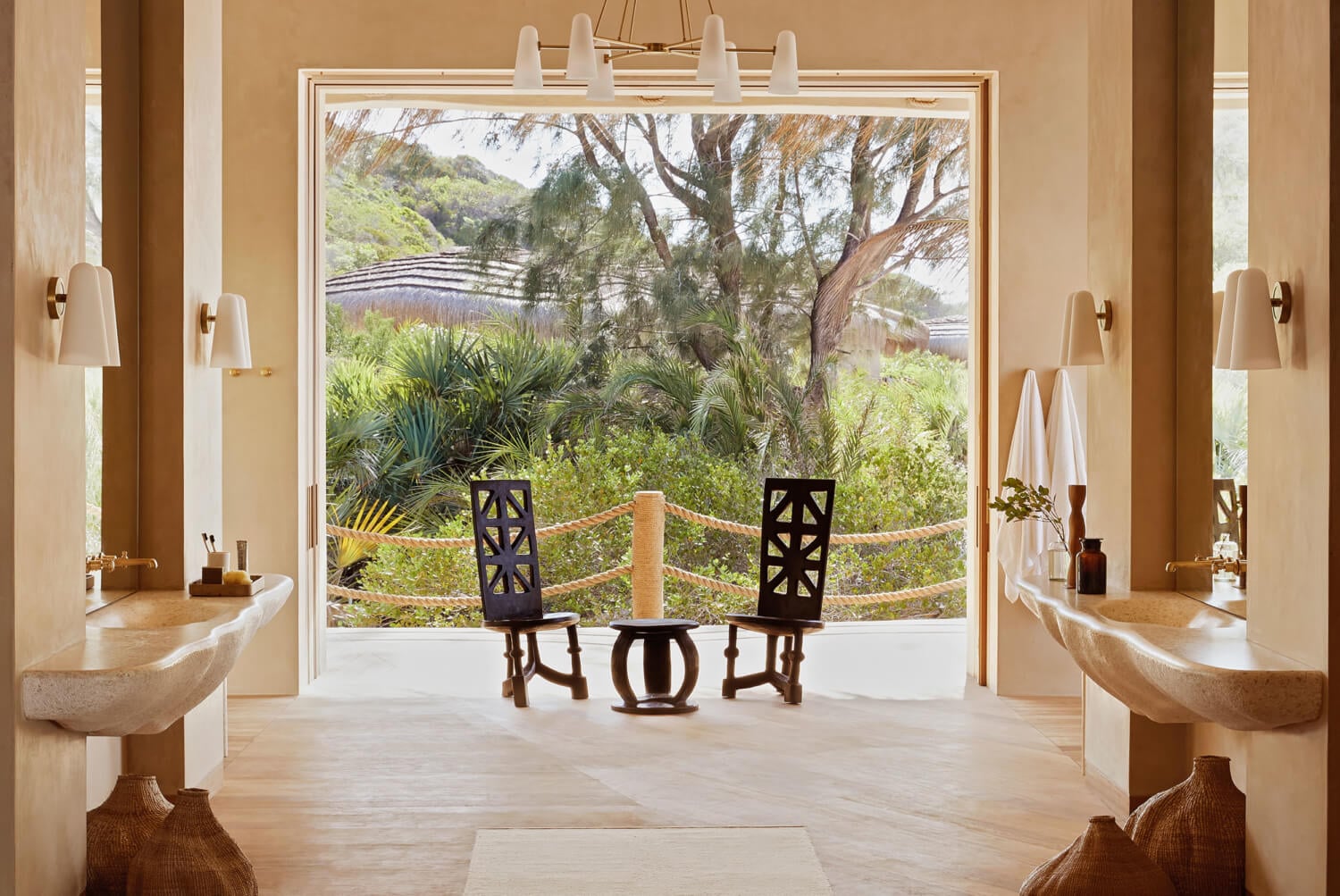 Kisawa Sanctuary, Africa — Spa bathroom with stone vessel sinks, wooden chairs, and panoramic views of lavender fields and acacia trees through glass doors.