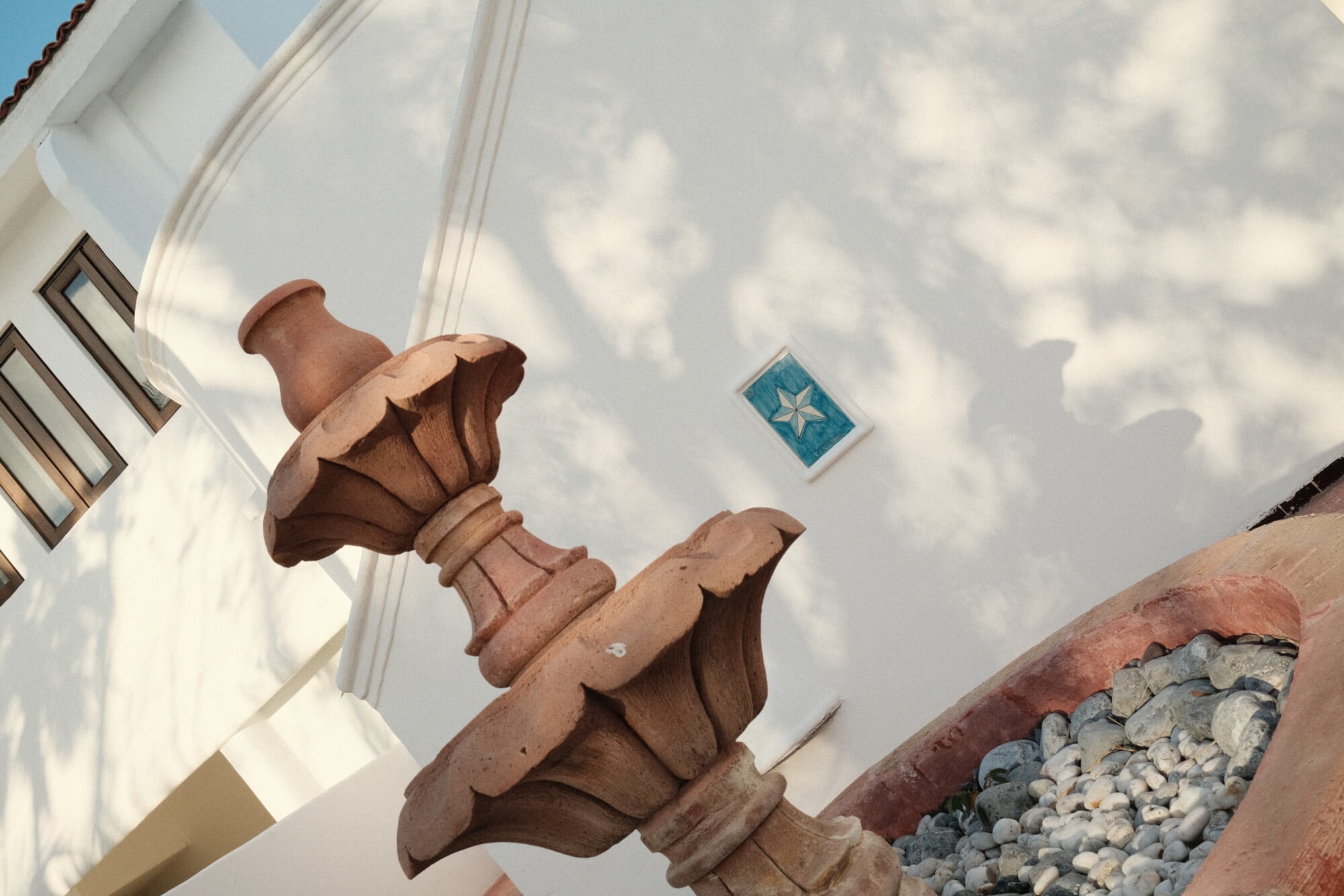 Maroma, A Belmond Hotel, Mexico — Terracotta architectural finial and blue tile detail on whitewashed facade with dappled light and coastal stone accents.