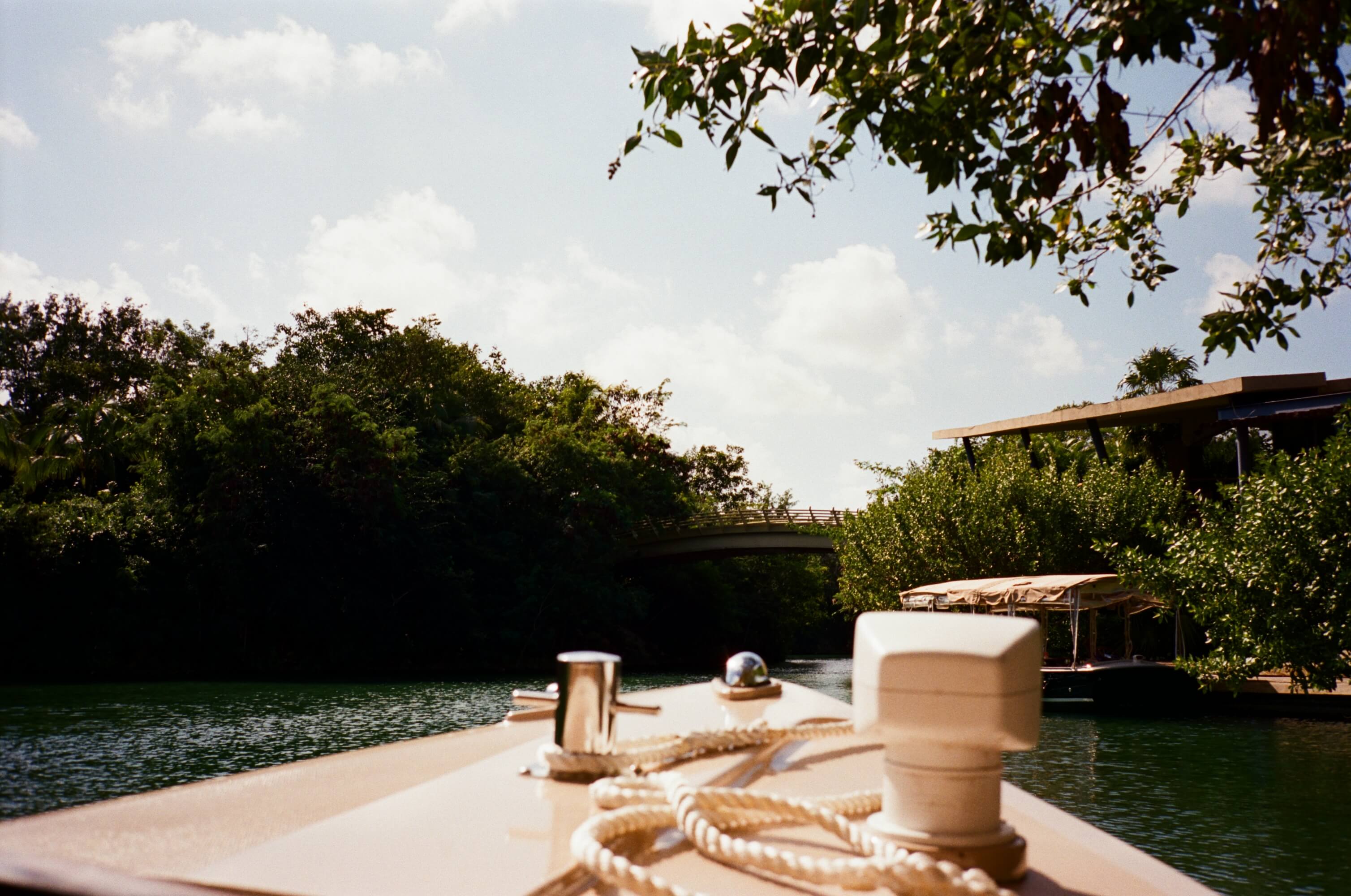 Rosewood Mayakoba, Mexico — Rope-wrapped dock cleats on wooden boat deck overlooking mangrove waterway with modern bridge and thatched structures.