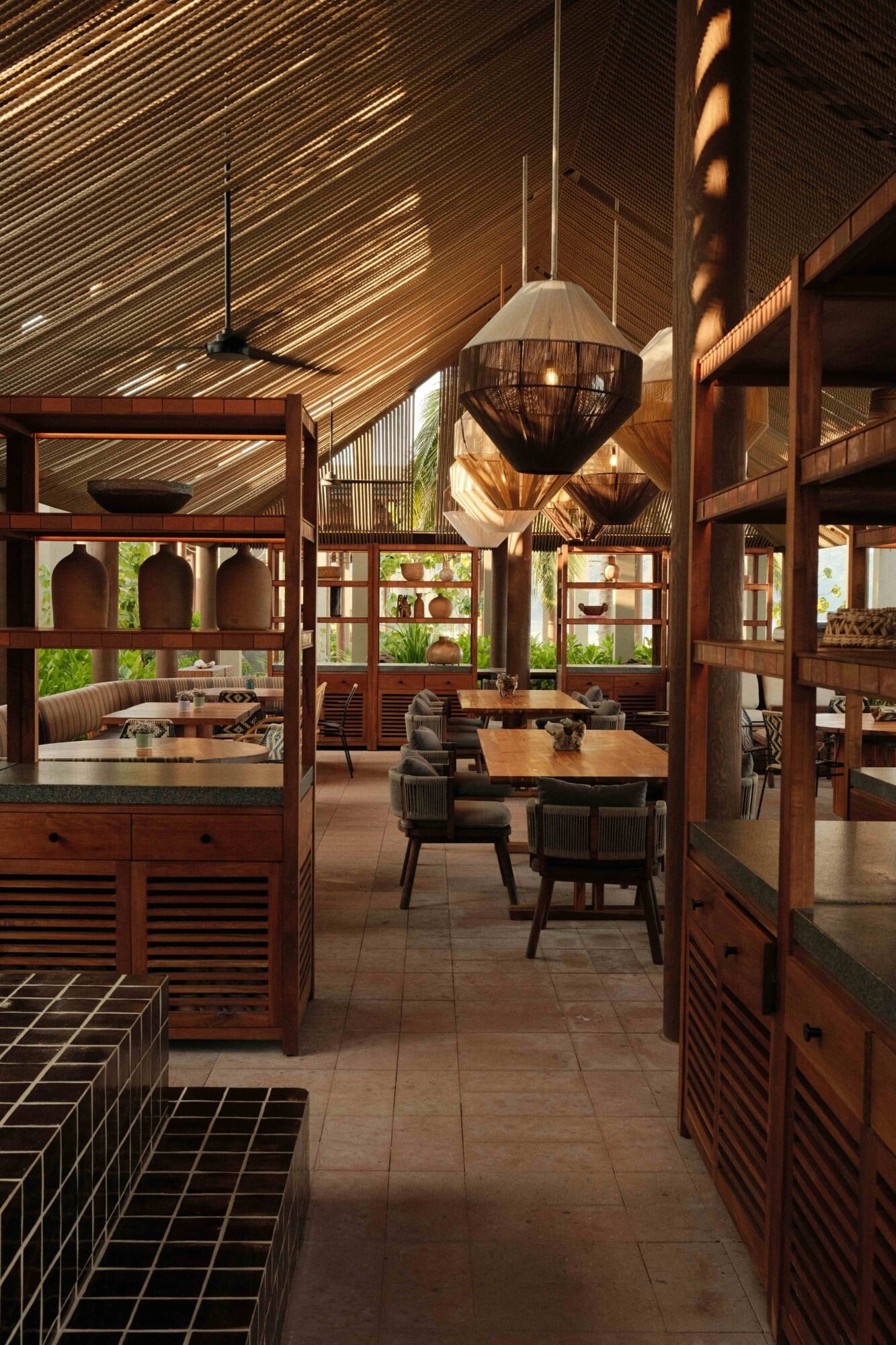 La Cocina Mandarina, Mexico — Wood-slat ceiling restaurant with pendant lights, teak furnishings, geometric tile floors, and garden views through slatted screens.