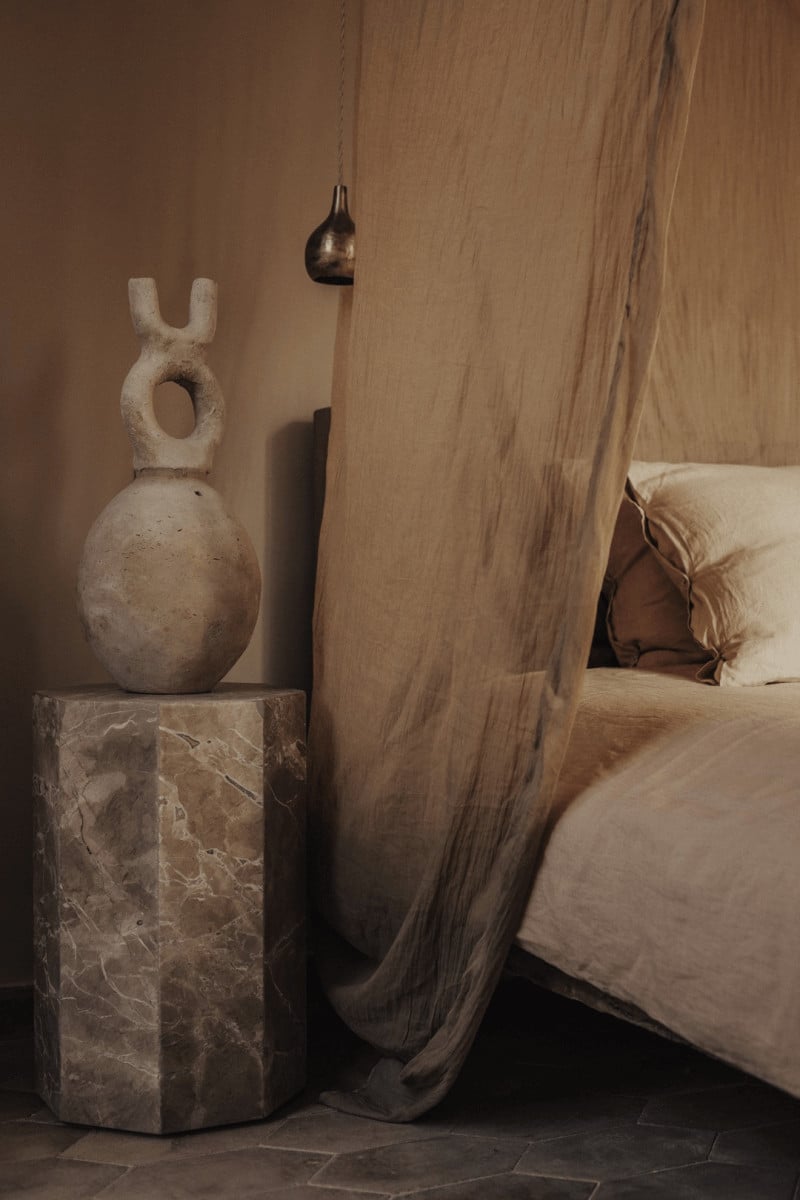 Hotel Corazón, Balearic Islands, Spain — Minimalist bedroom with marble pedestal, sculptural stone object, dark pendant lamp, linen curtains and neutral bedding.