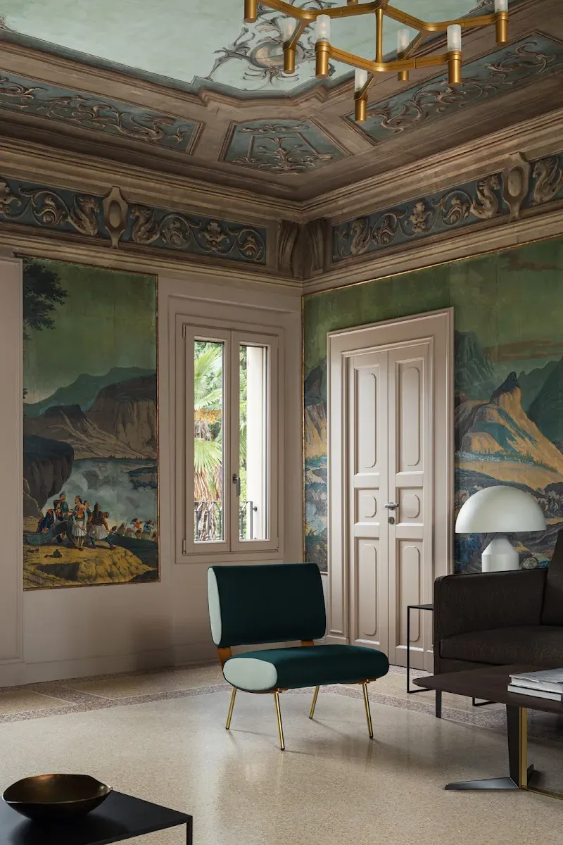 Roncolo 1888, Europe — Neoclassical room with ornate ceiling, landscape murals, brass pendant light, and contemporary furniture in muted tones.