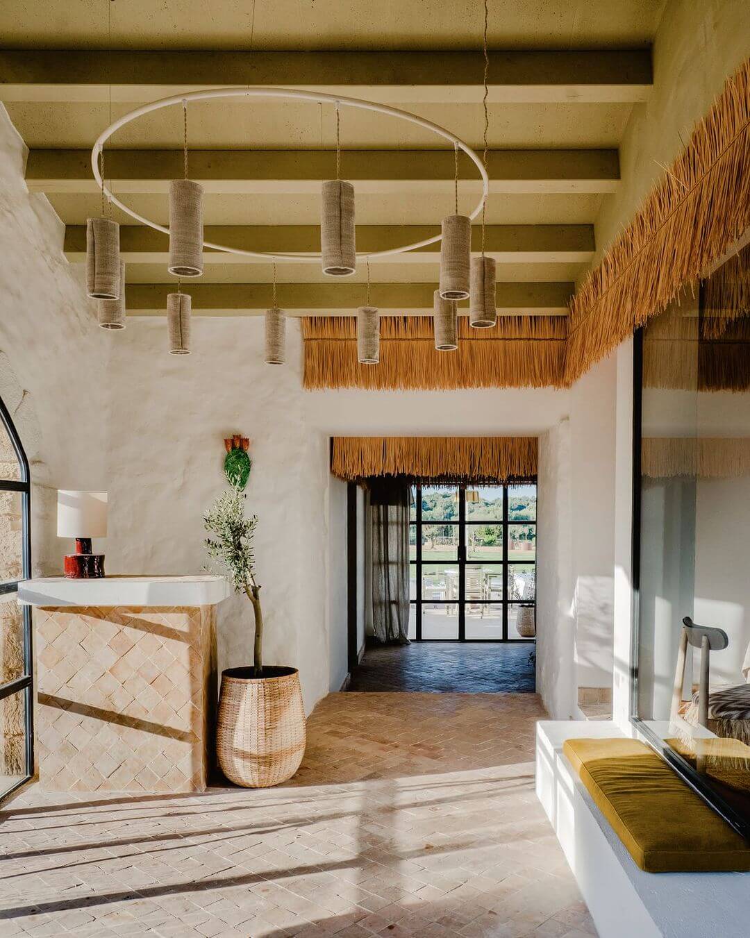 Amagatay, Balearic Islands, Spain — Minimalist spa reception with woven pendant lights, whitewashed walls, natural materials, and framed windows overlooking countryside.