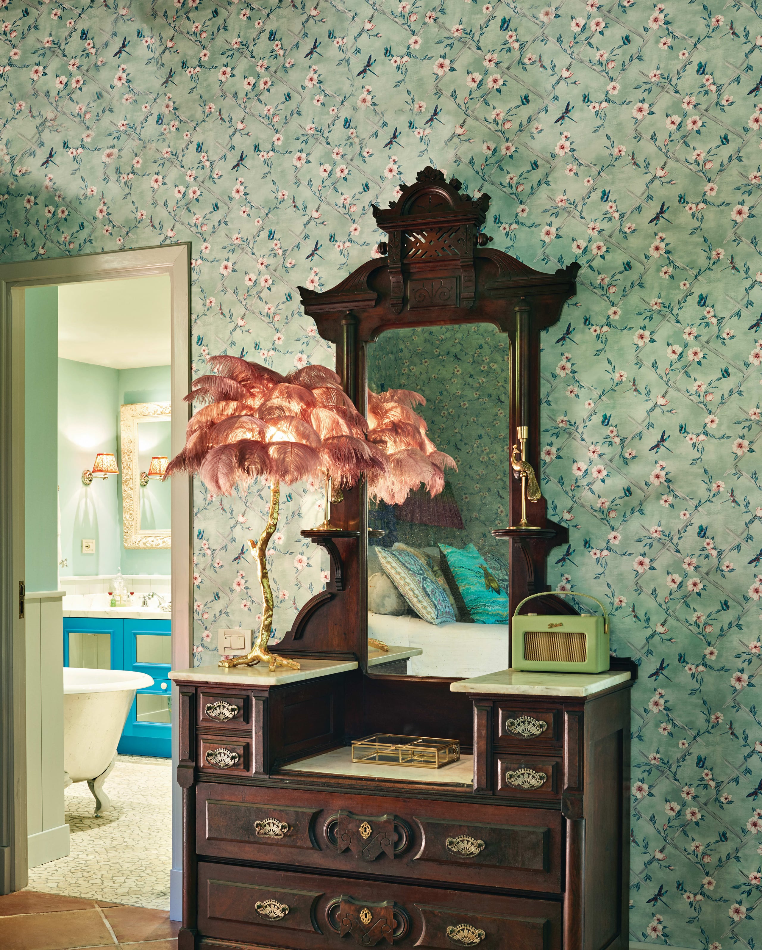 Belmond La Residencia, Balearic Islands, Spain — Dark wood canopy bed with ornate mirror, pink feathered lamp, floral wallpaper, luxe bedroom interior design.
