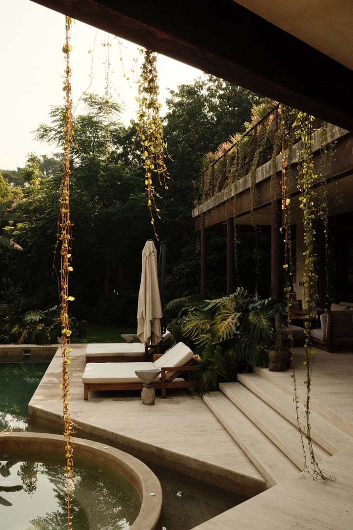 Casa Lumeria, Mexico — Modernist poolside pavilion with hanging vines, wooden lounge chairs, and lush jungle canopy at golden hour.