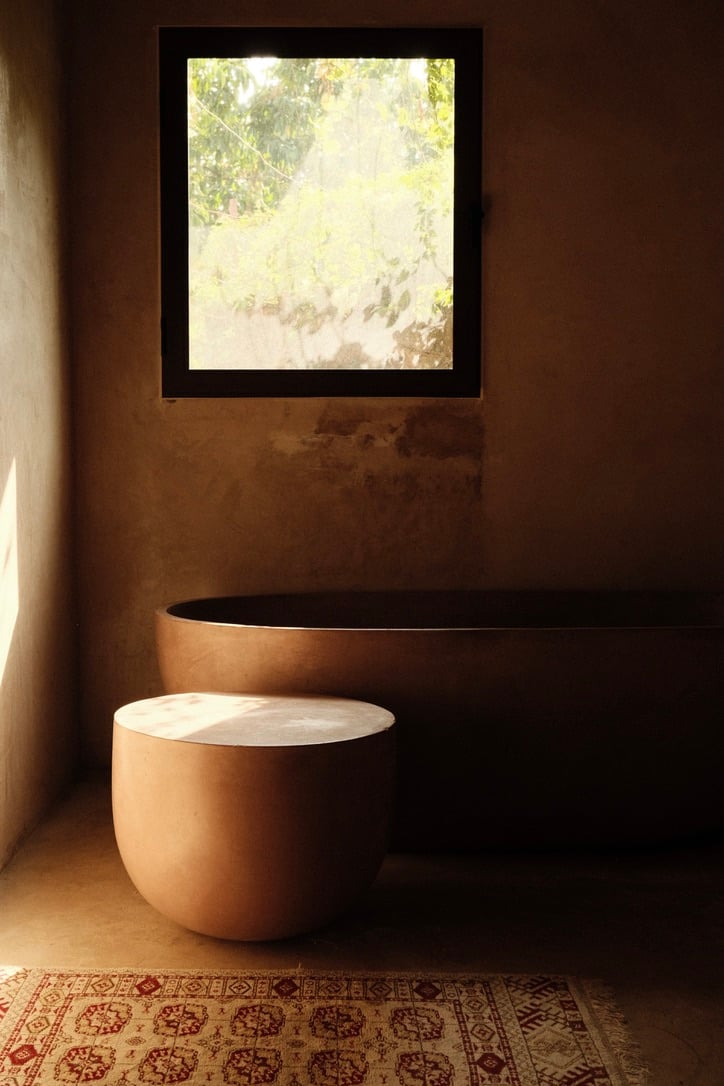 Casa Lumeria, Mexico — Minimalist interior with terracotta vessels, wooden window frame, dappled natural light, geometric tile floor, earthy tones, serene architectural design.