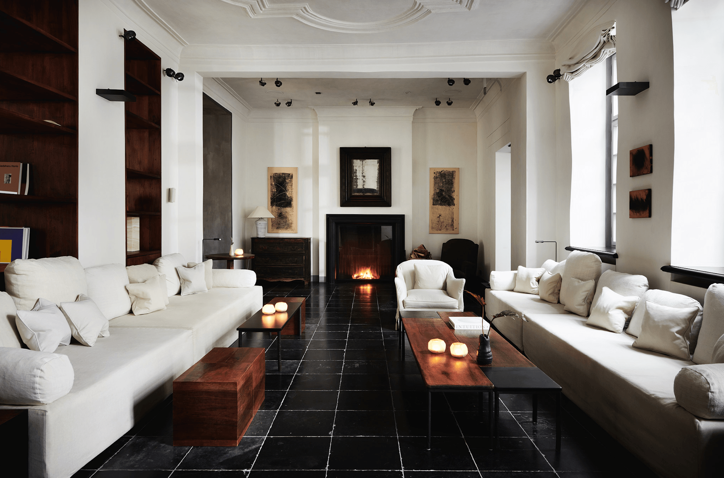 Purs, Europe — Modern luxury lounge with cream seating, black fireplace, dark tile flooring, and contemporary art in minimalist design.