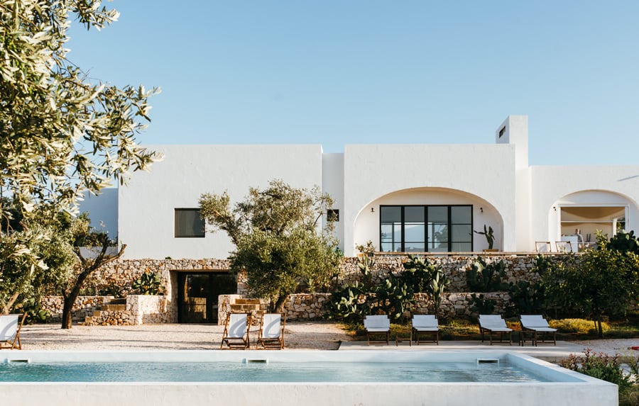 Masseria Moroseta, Europe — Whitewashed Mediterranean villa with curved archways, stone terrace, olive trees, and modernist pool under clear sky.