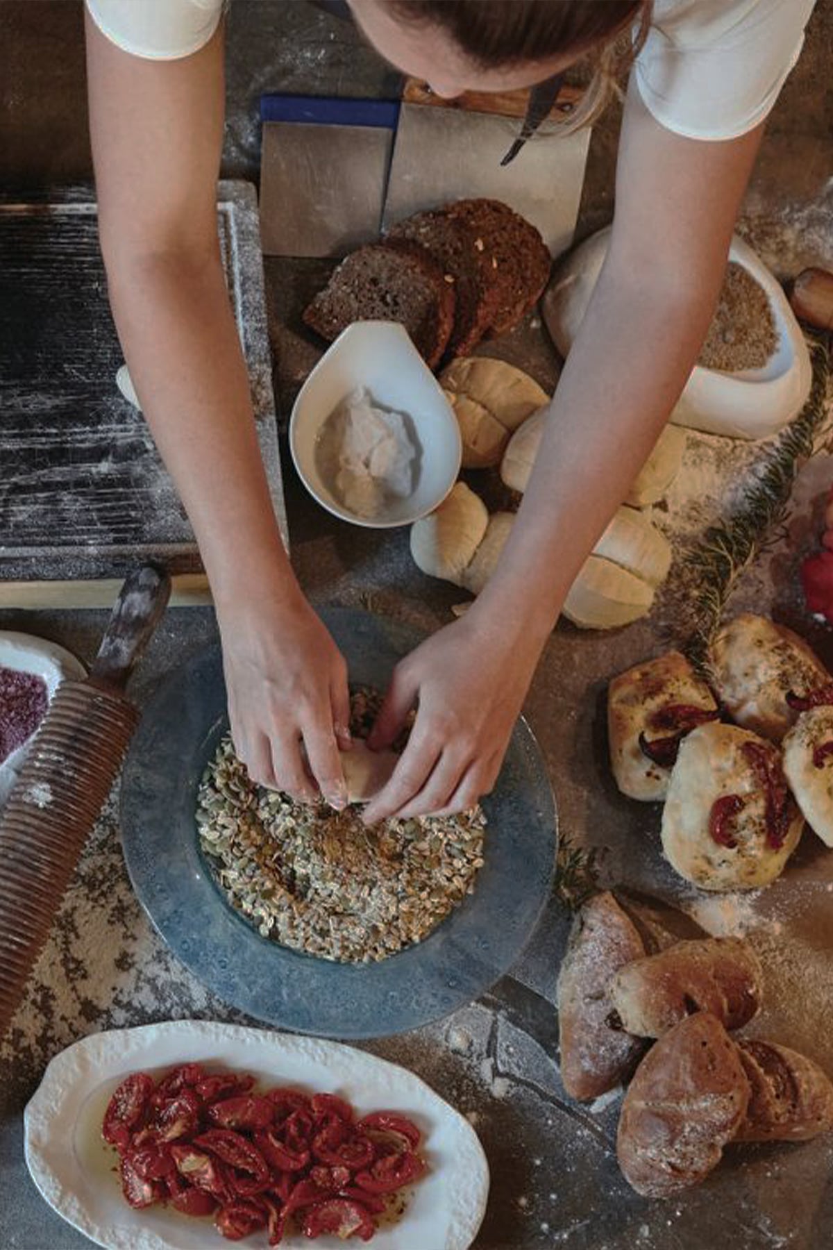 Restaurants In North Western Mallorca — Hands grinding grains in stone mortar with traditional Mallorcan ingredients, bread, cured meats, and fresh produce arranged on rustic work surface.