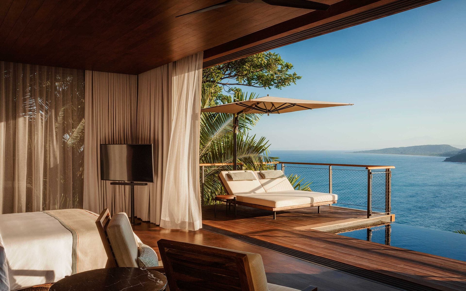 One&Only Mandarina, Mexico — Oceanfront suite with teak deck, cream loungers under cantilever umbrella, floor-to-ceiling curtains, and unobstructed Pacific views.