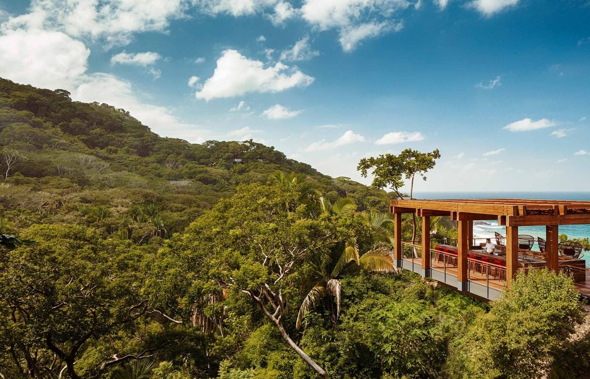 One&Only Mandarina, Mexico — Wooden terrace pavilion overlooking lush tropical hillside and ocean horizon, mid-century modern architecture with coastal views.