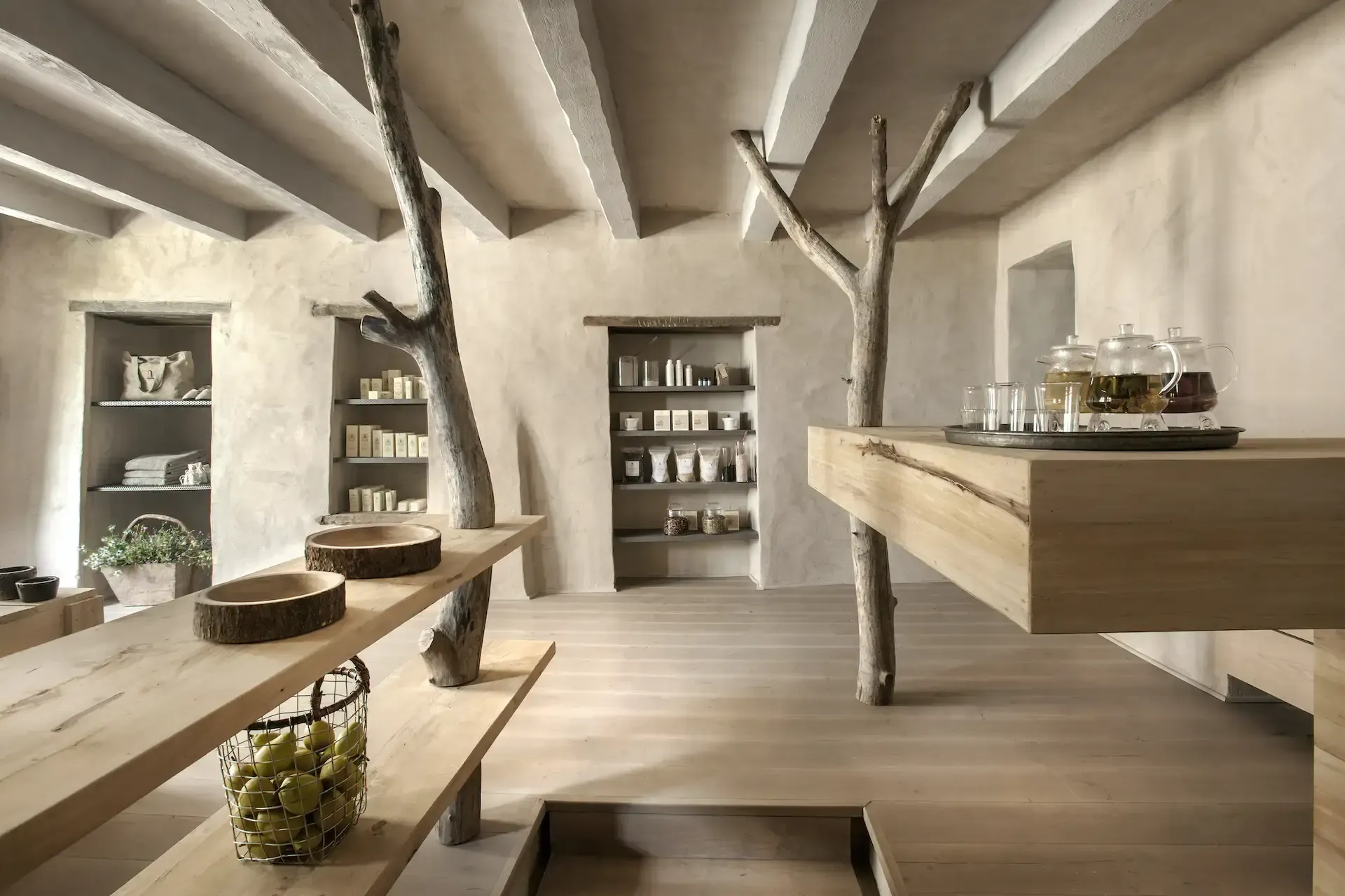 Spa Center, Europe — Minimalist wellness interior with whitewashed walls, exposed wooden beams, natural light, stone basins, wooden counters, shelved product displays, and organic architectural elements.